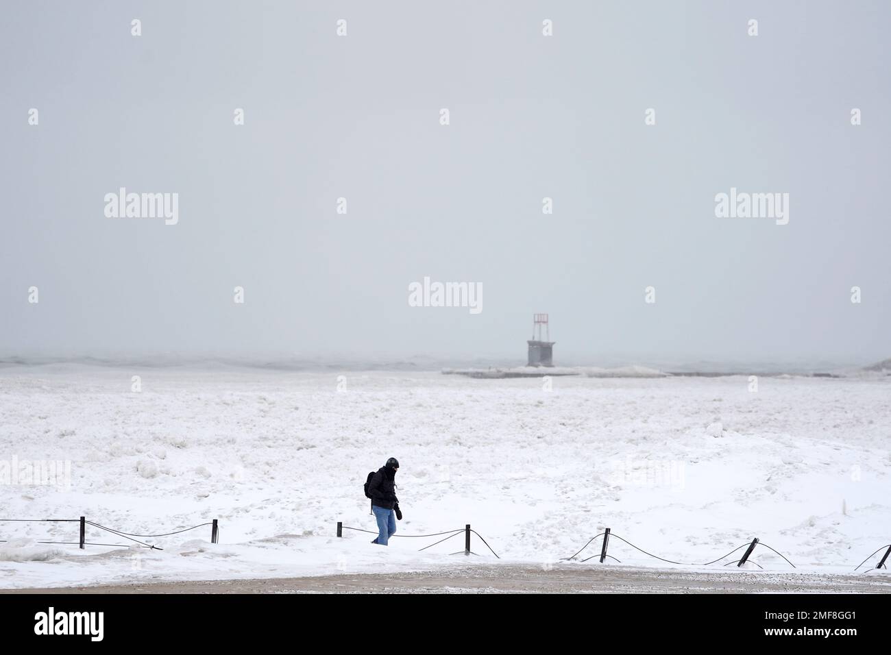 A lone man walks along a frozen section of North Ave. beach on Lake Michigan north of downtown Chicago Tuesday, Jan. 26, 2021. A major winter storm dumped more than a foot of snow on parts of the middle of the country stretching from central Kansas northeast to Chicago and southern Michigan.(AP Photo/Charles Rex Arbogast) Banque D'Images