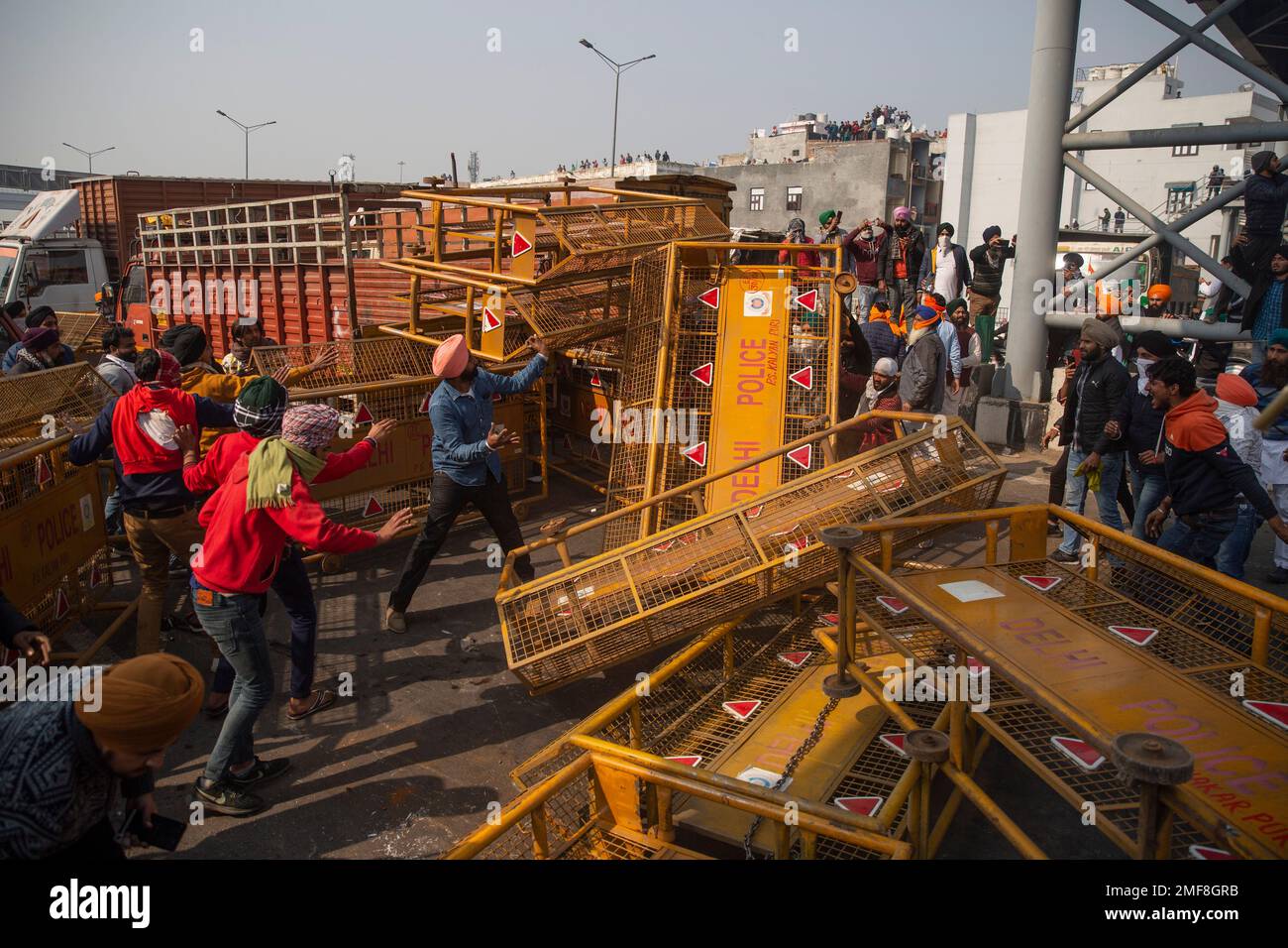 Protesting farmers remove police barricades as they march to the capital during India's Republic Day celebrations in New Delhi, India, Tuesday, Jan. 26, 2021. Tens of thousands of farmers drove a convoy of tractors into the Indian capital as the nation celebrated Republic Day on Tuesday in the backdrop of agricultural protests that have grown into a rebellion and rattled the government. (AP Photo/Altaf Qadri) Banque D'Images