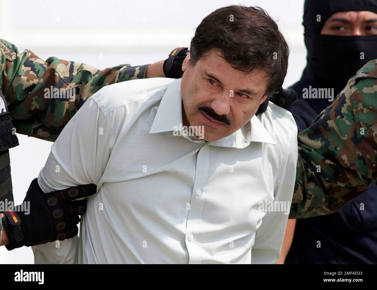 FILE - In this Feb. 22, 2014 file photo, Joaquin "El Chapo" Guzman, the head of Mexico's Sinaloa Cartel, is escorted to a helicopter in Mexico City following his capture in the beach resort town of Mazatlan, Mexico. The Mexican drug kingpin, who was convicted in a New York federal court in February 2019 on multiple conspiracy counts in an epic drug-trafficking case, was sentenced to life behind bars in a U.S. prison. (AP Photo/Eduardo Verdugo, File) Banque D'Images