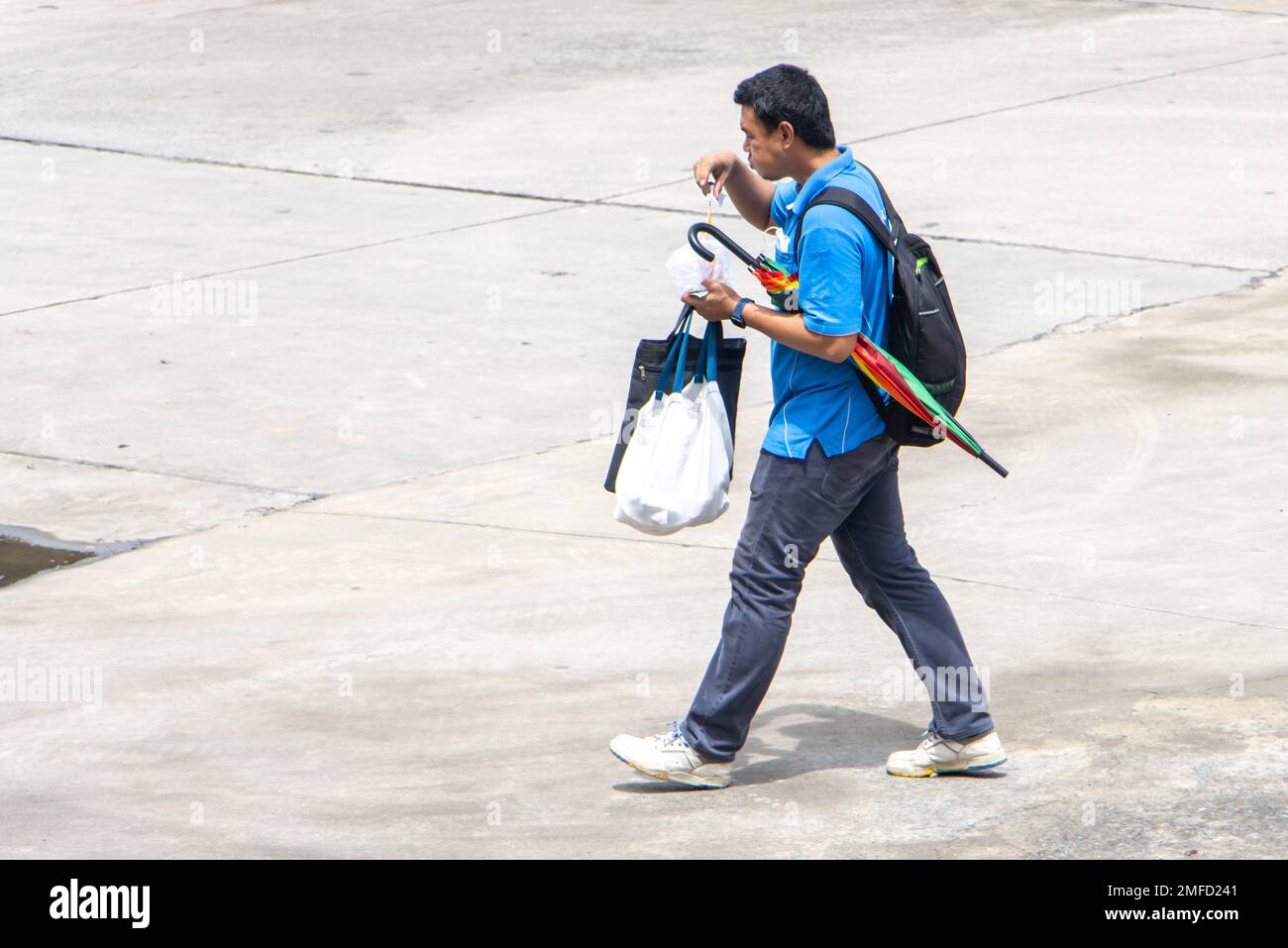 SAMUT PRAKAN, THAÏLANDE, OCT 10 2022, Un homme avec des sacs descend la rue et mange un meatball du marché Banque D'Images