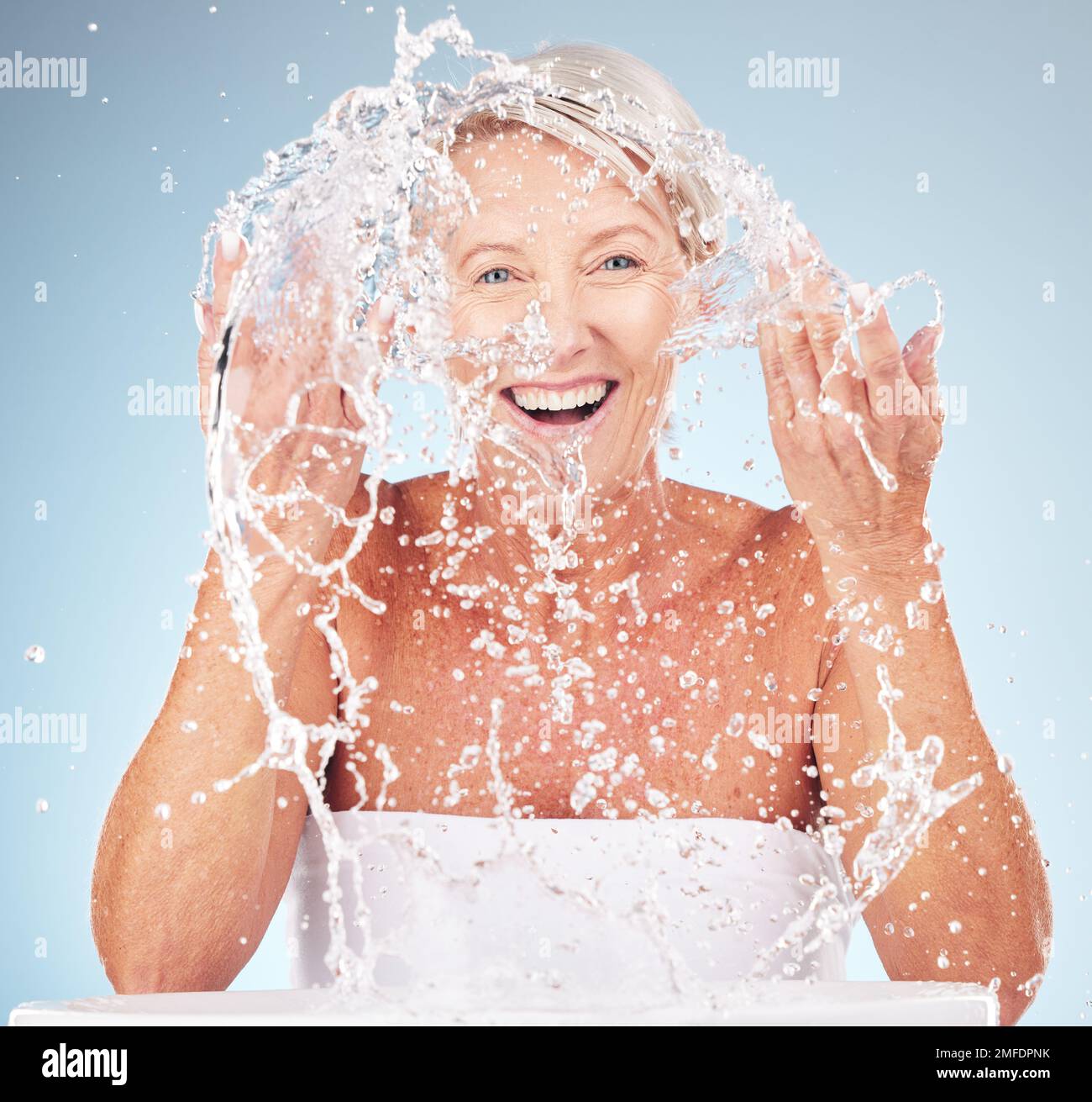 Douche, visage et vieille femme avec le sourire et l'eau éclabousse, peau propre et antiâge beauté, modèle âgé isolé sur fond de studio. Soins de la peau senior Banque D'Images
