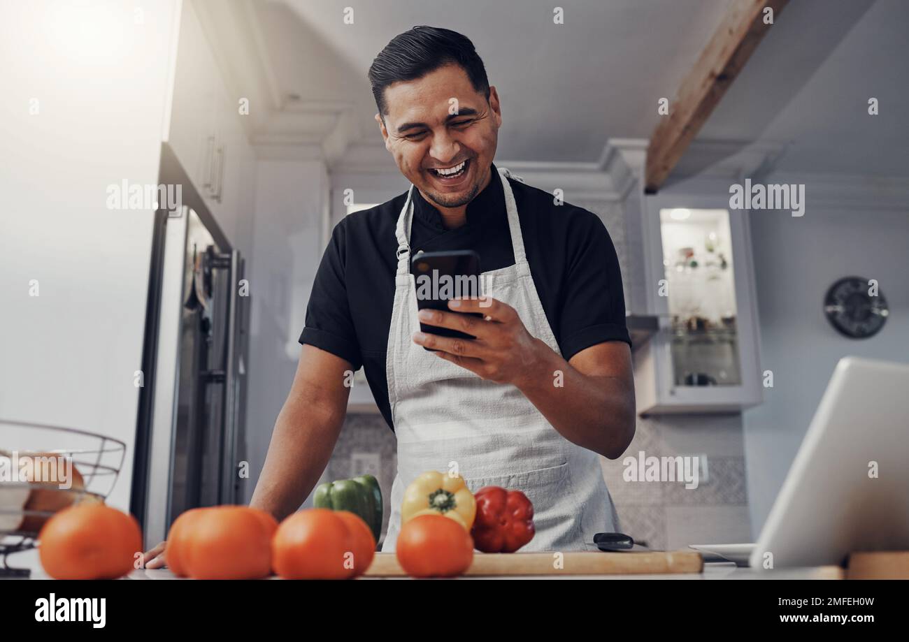 Homme, cuisiner des légumes et téléphone pour comic recette en ligne dans la cuisine avec connexion wifi maison. Chef avec application mobile pour apprendre ou publier un blog Banque D'Images
