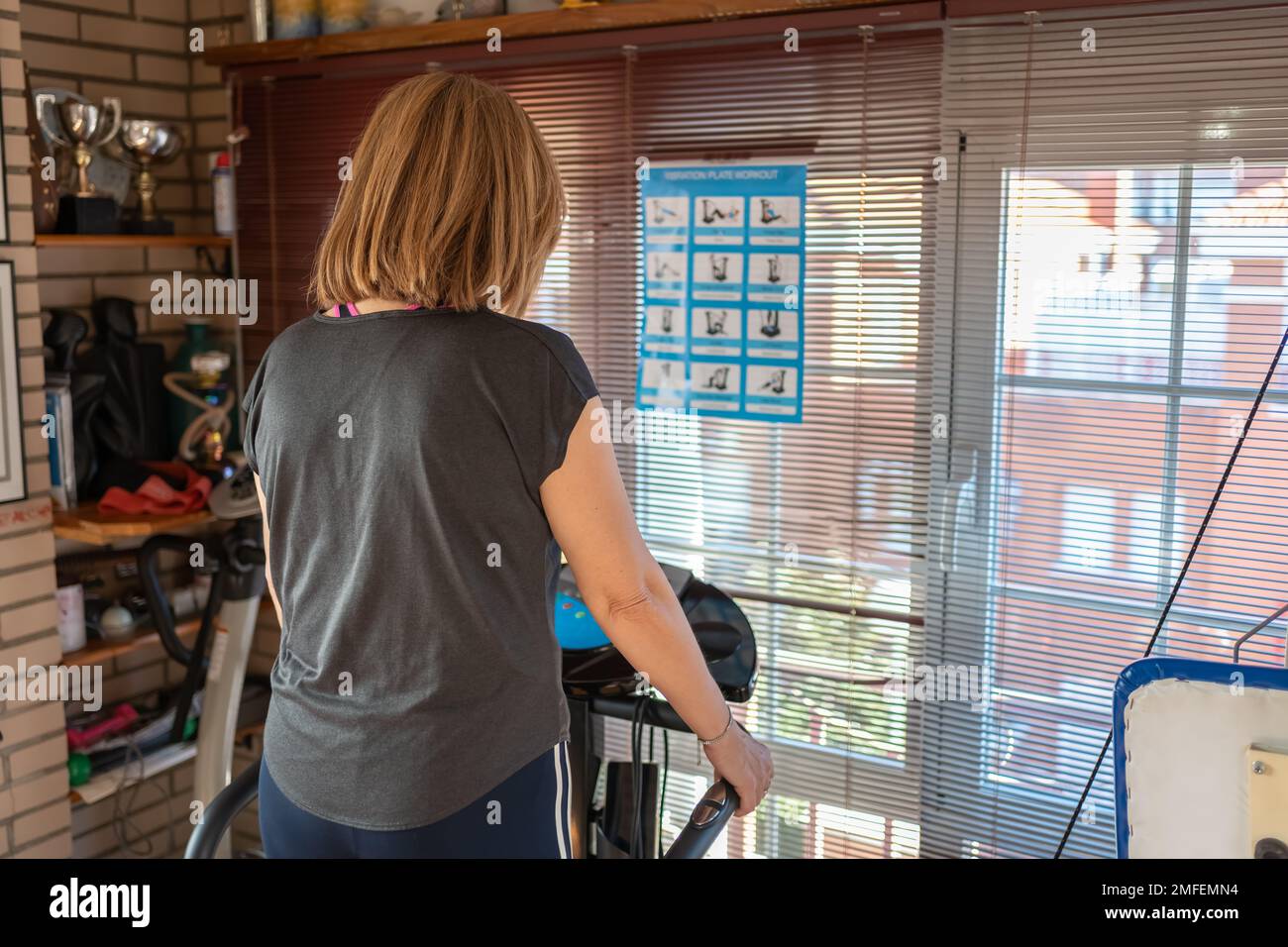 Femme blanche sur une machine de gymnastique vibrante pour exercer des muscles et garder la forme à la maison. Banque D'Images