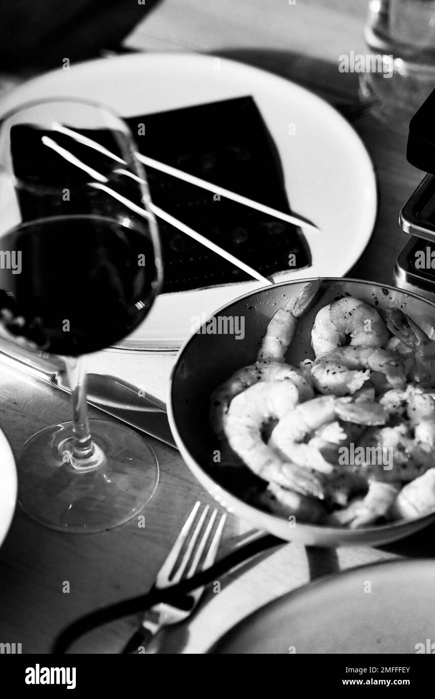 Une photo verticale monochrome des crevettes frites avec un verre de vin Banque D'Images