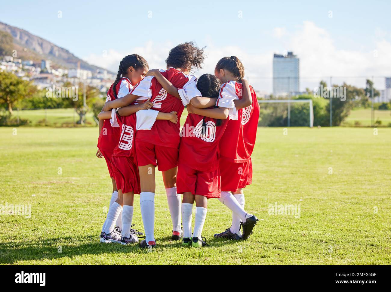Diversité, sport girl hug et entraînement de terrain de football pour les jeunes de compétition jouant à l'herbe de stade. L'équipe, le jeune athlète ou le joueur aiment Banque D'Images
