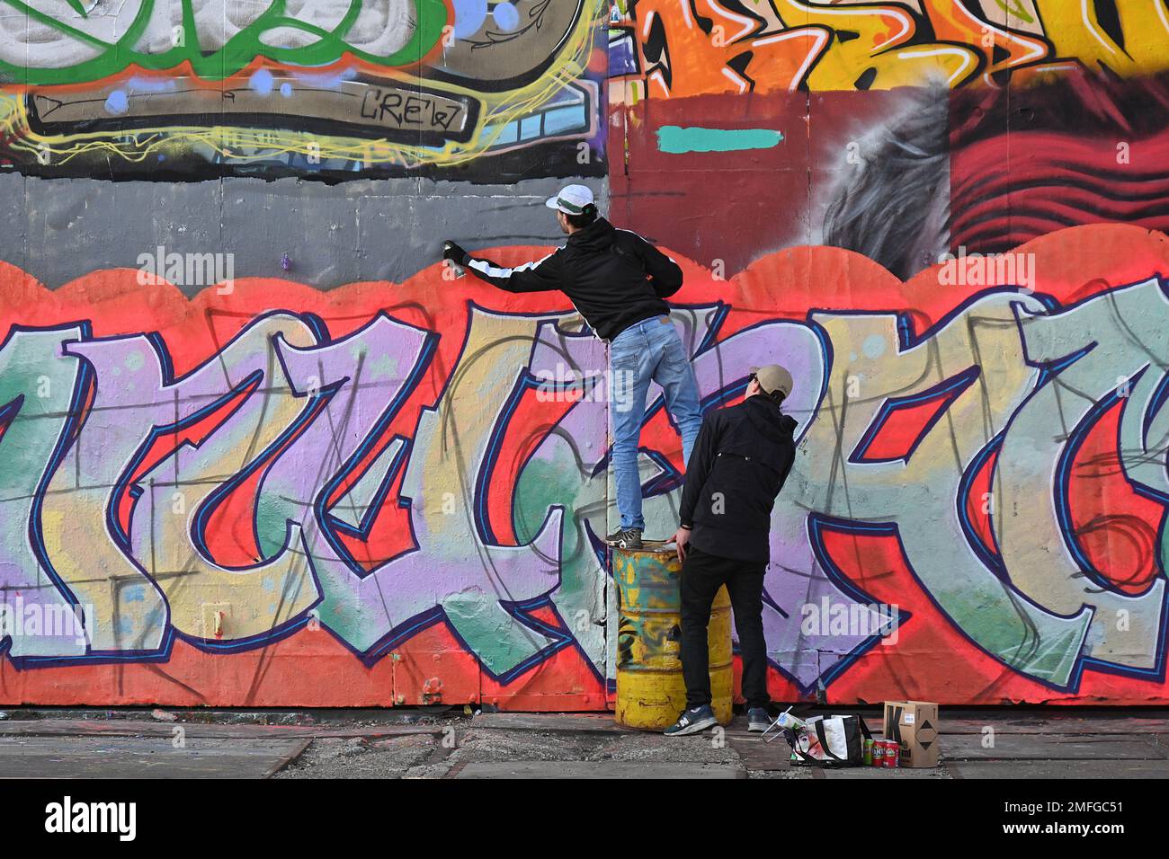 Pays-Bas, Amsterdam : artistes de rue à l'œuvre, réalisant des peintures murales colorées sur les murs du Musée Straat (graffiti et musée d'art de rue) à ND Banque D'Images