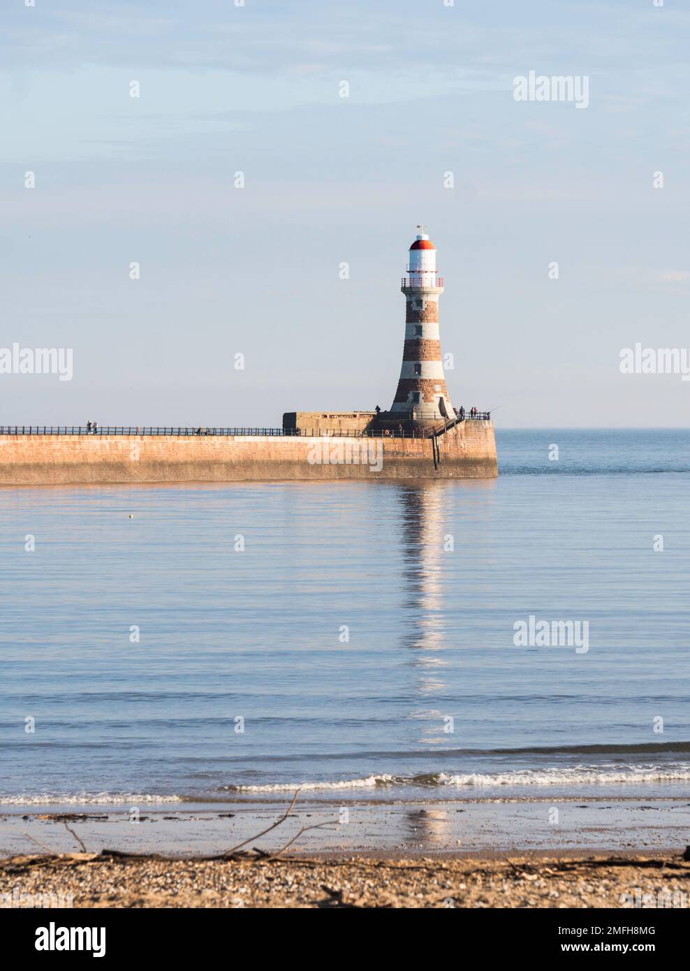 Météo au Royaume-Uni 24-1-2023 le phare de Roker se reflète dans une mer lisse, Sunderland, Angleterre, Royaume-Uni Banque D'Images