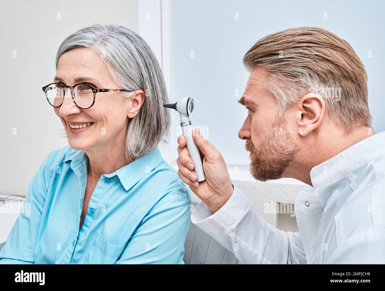 Otolaryngologiste médecin vérifiant l'oreille d'une femme mature à l'aide d'un otoscope ou d'un auriscope à la clinique ORL. Examen d'audition Banque D'Images