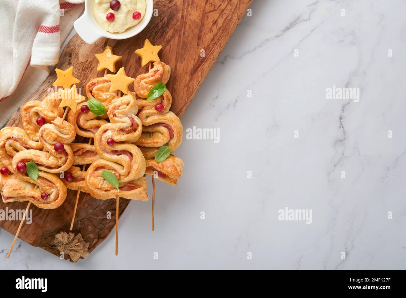 Hors-d'œuvre de Noël ou du nouvel an. Petits pains de pâte feuilletée en forme d'arbre de Noël avec fromage et jambon. Groupe de formes d'arbre de Noël sur panneau en bois. Carte d'identité festive Banque D'Images