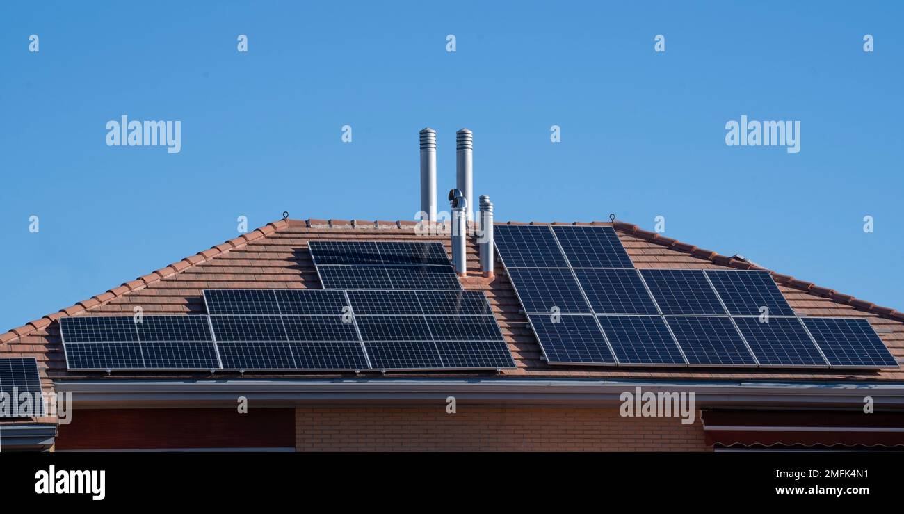 Panneaux solaires sur un toit carrelé contre un ciel bleu avec espace de copie Banque D'Images