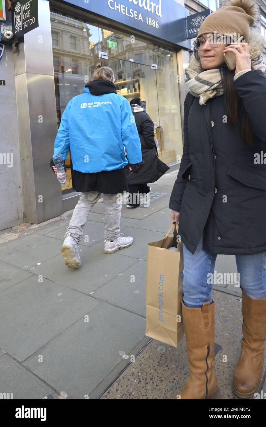 Londres, Angleterre, Royaume-Uni. Femme sur son téléphone portable à Oxford Street par temps froid Banque D'Images