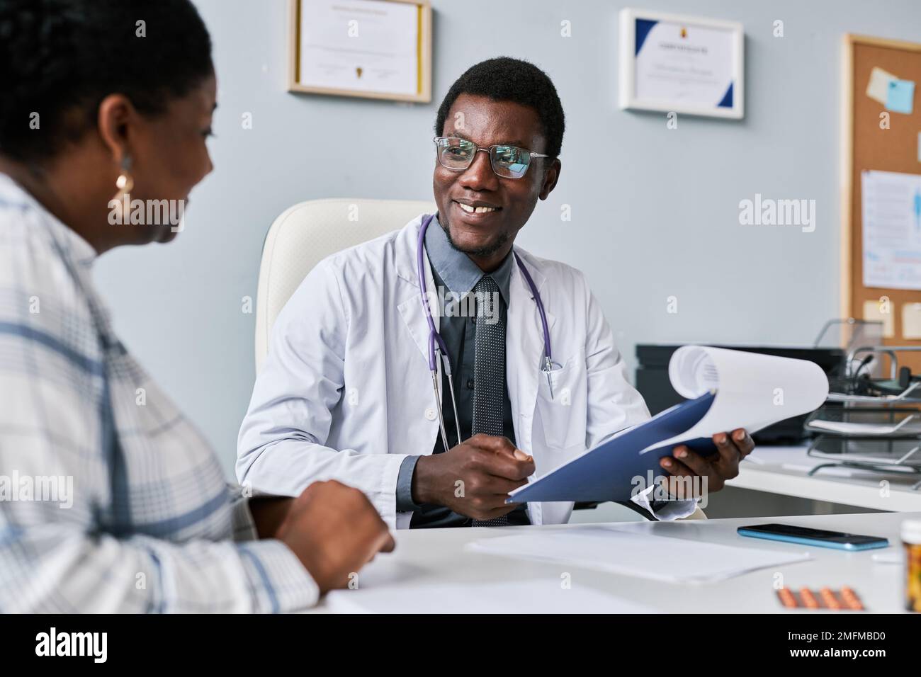 Portrait d'un médecin noir souriant consultant une femme médecin dans une clinique privée Banque D'Images Portrait d'un médecin noir souriant consultant une femme médecin dans une clinique privée Banque D'Images