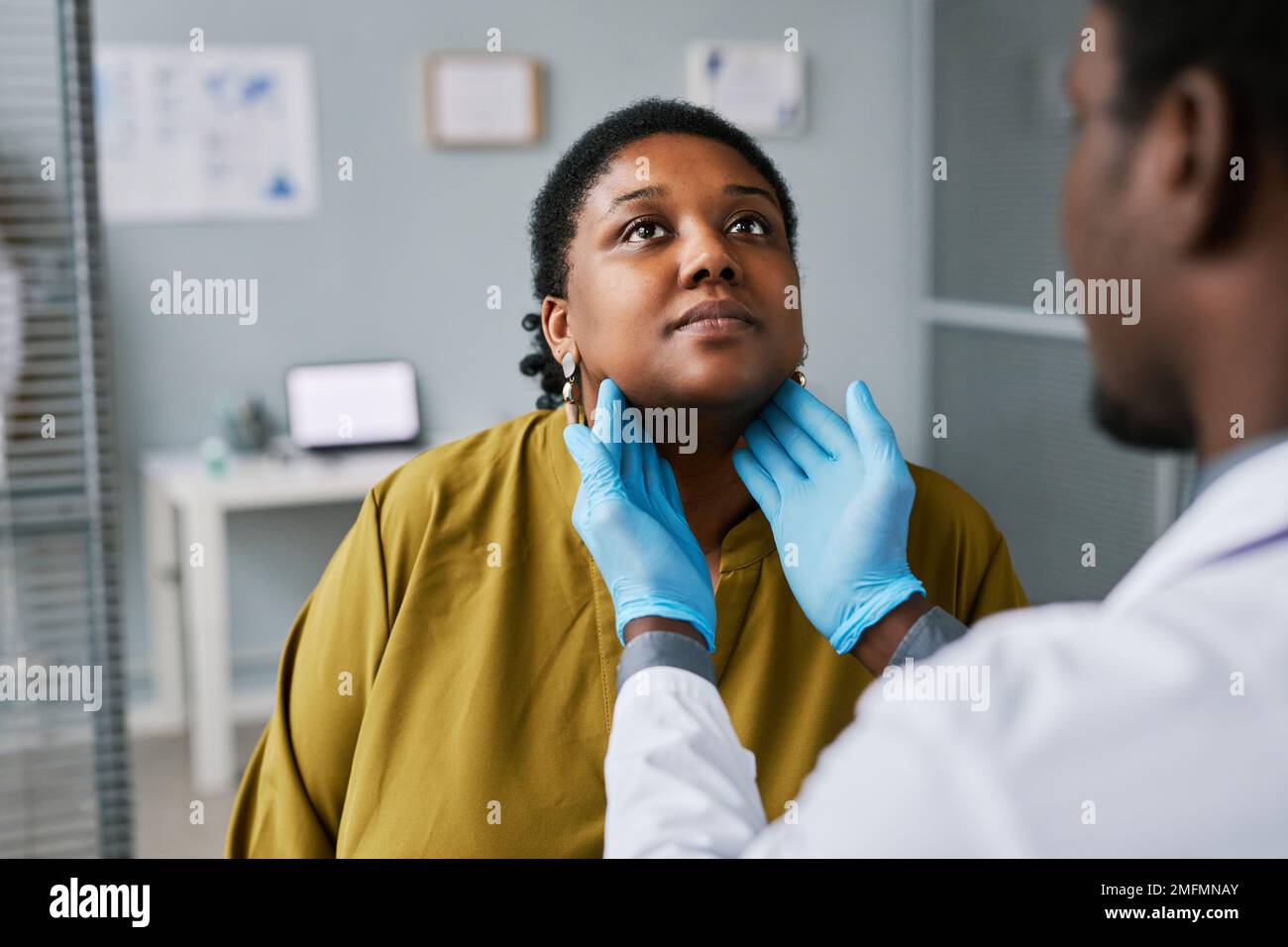 Portrait de la femme noire au bilan de santé avec un médecin qui palpe le cou Banque D'Images