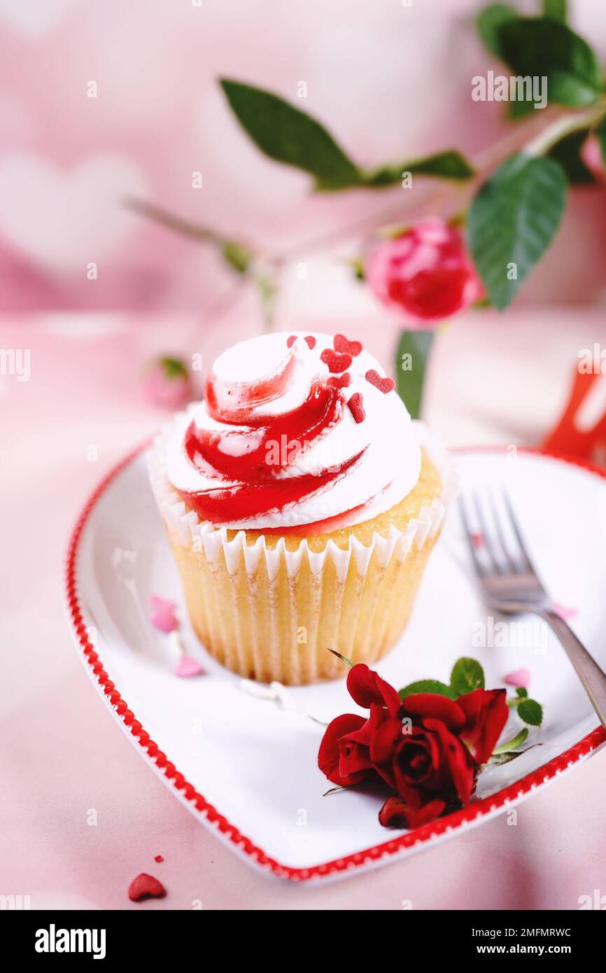 Saint-Valentin tourbillons de cupcake avec glaçage blanc rouge et roses | fond de dessert de jour de Saint-Valentin, foyer sélectif Banque D'Images