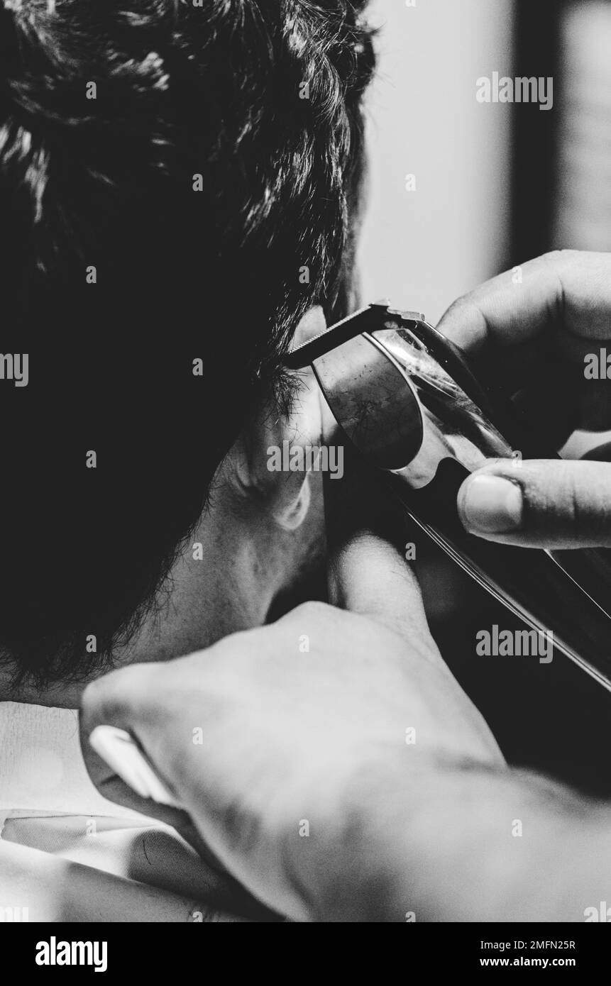Un jeune homme caucasien obtient une coupe de cheveux et se rasent d'un coiffeur dans un salon de coiffure Banque D'Images