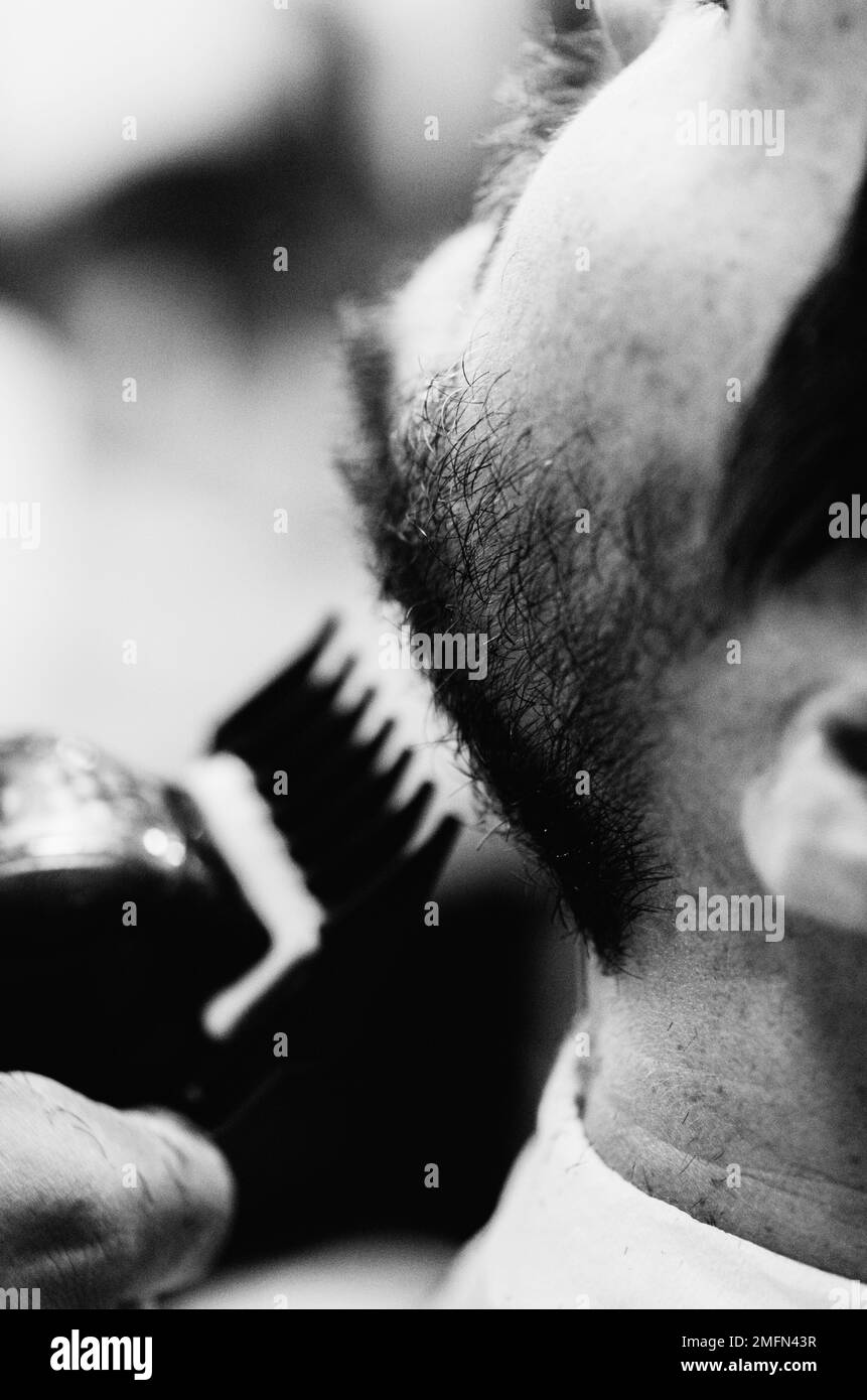 Un jeune homme caucasien obtient une coupe de cheveux et se rasent d'un coiffeur dans un salon de coiffure Banque D'Images