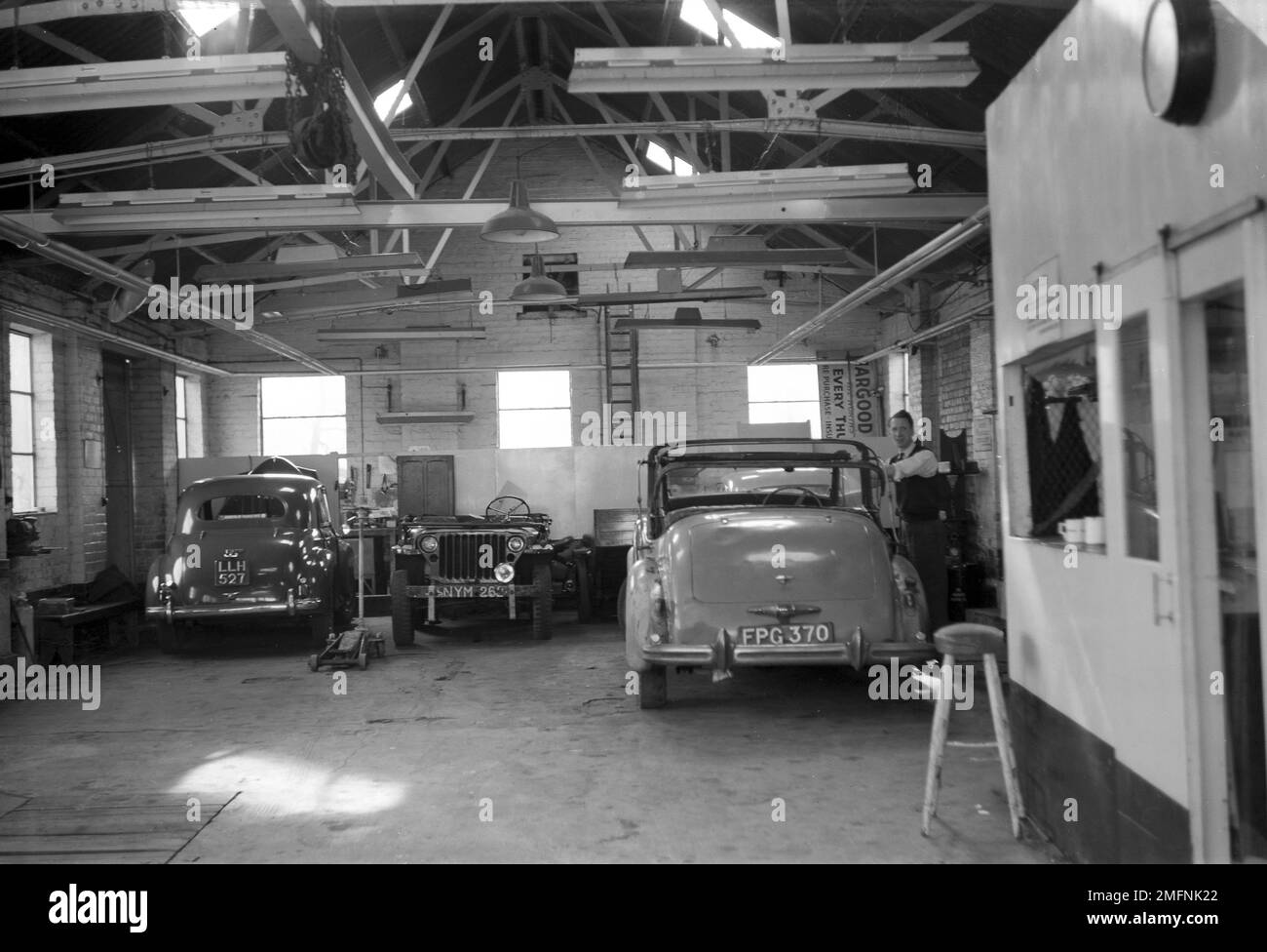 1950s, historique, vue arrière de deux voitures de l'époque garées à l'intérieur du garage à Hargood Motor Sales, Parrs Wood, East Didsbury, Manchester, Angleterre, ROYAUME-UNI. Banque D'Images