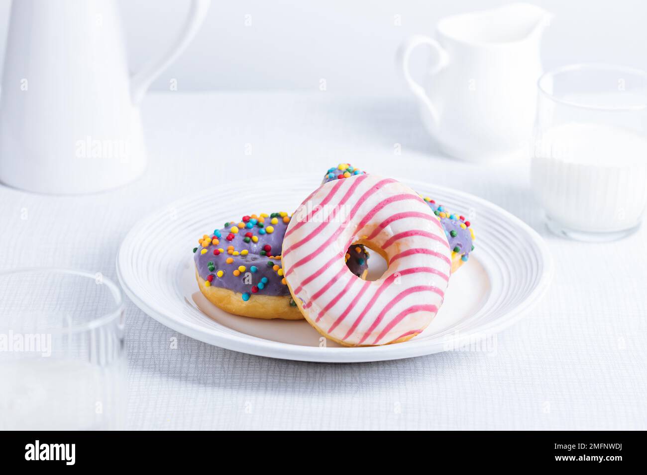 Beignets américains sur plaque blanche sur fond clair. Image ludique et colorée de bonbons et desserts. Banque D'Images