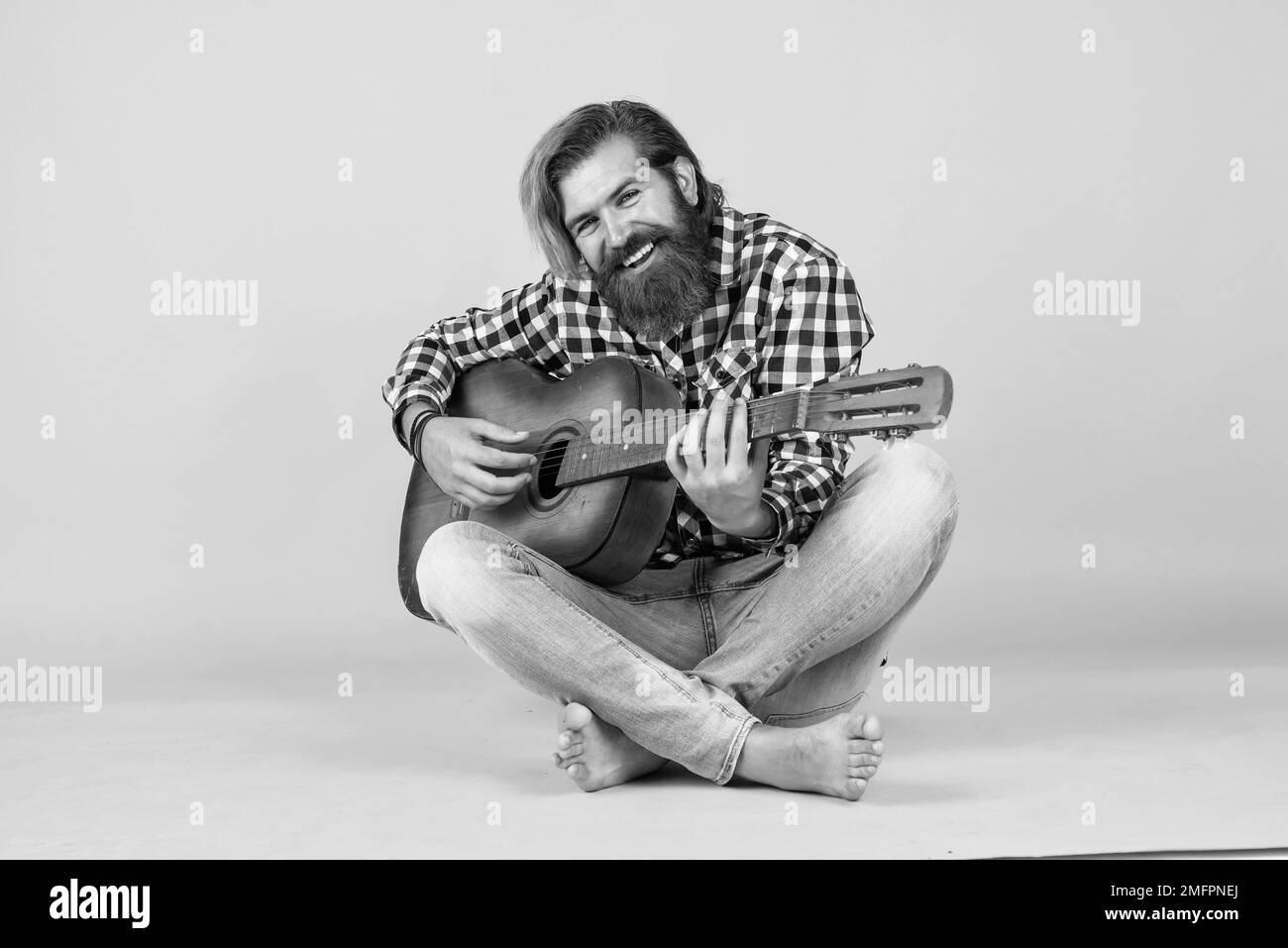 Utilisé pour être parfait. Son préféré.Portrait de joyeux barbu homme jouant de la guitare. Un musicien solitaire. Gai beau et beau homme mature jouant de la guitare et Banque D'Images