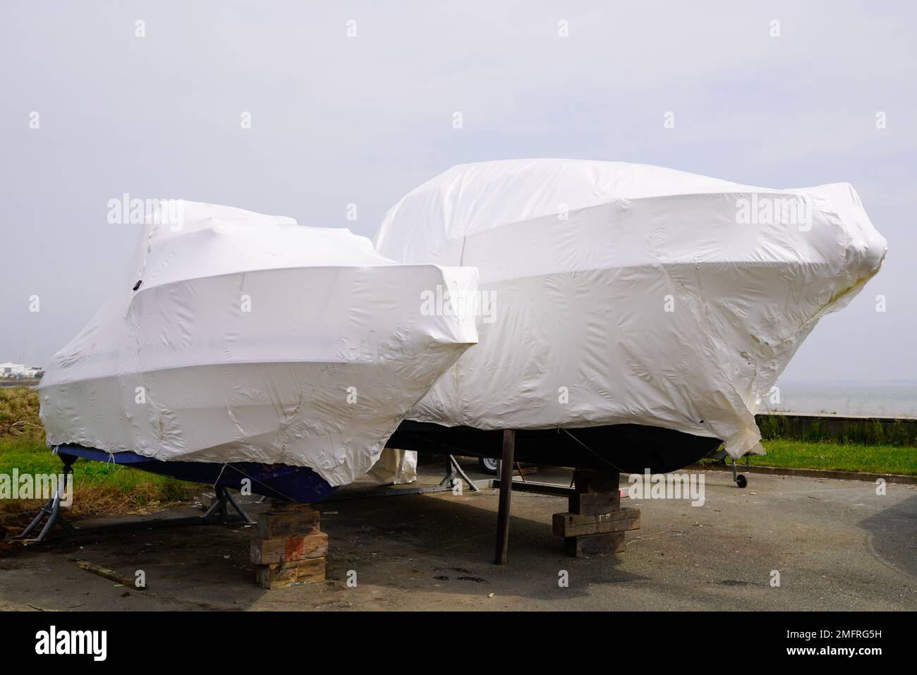 Bateau à moteur à l'eau garée protégé par un film plastique pour l'hivernage de nouveaux bateaux dans un enveloppe enveloppante enveloppante rétractable sur un voilier entreposé pour l'hiver Banque D'Images