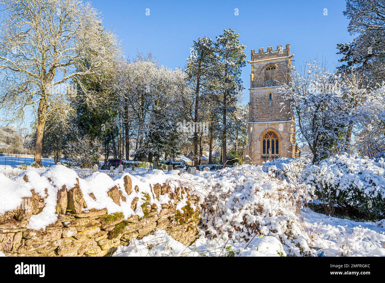 Début hiver neige à l'église de St John l'évangéliste dans le village Cotswold d'Elkstone, Gloucestershire, Angleterre Royaume-Uni Banque D'Images