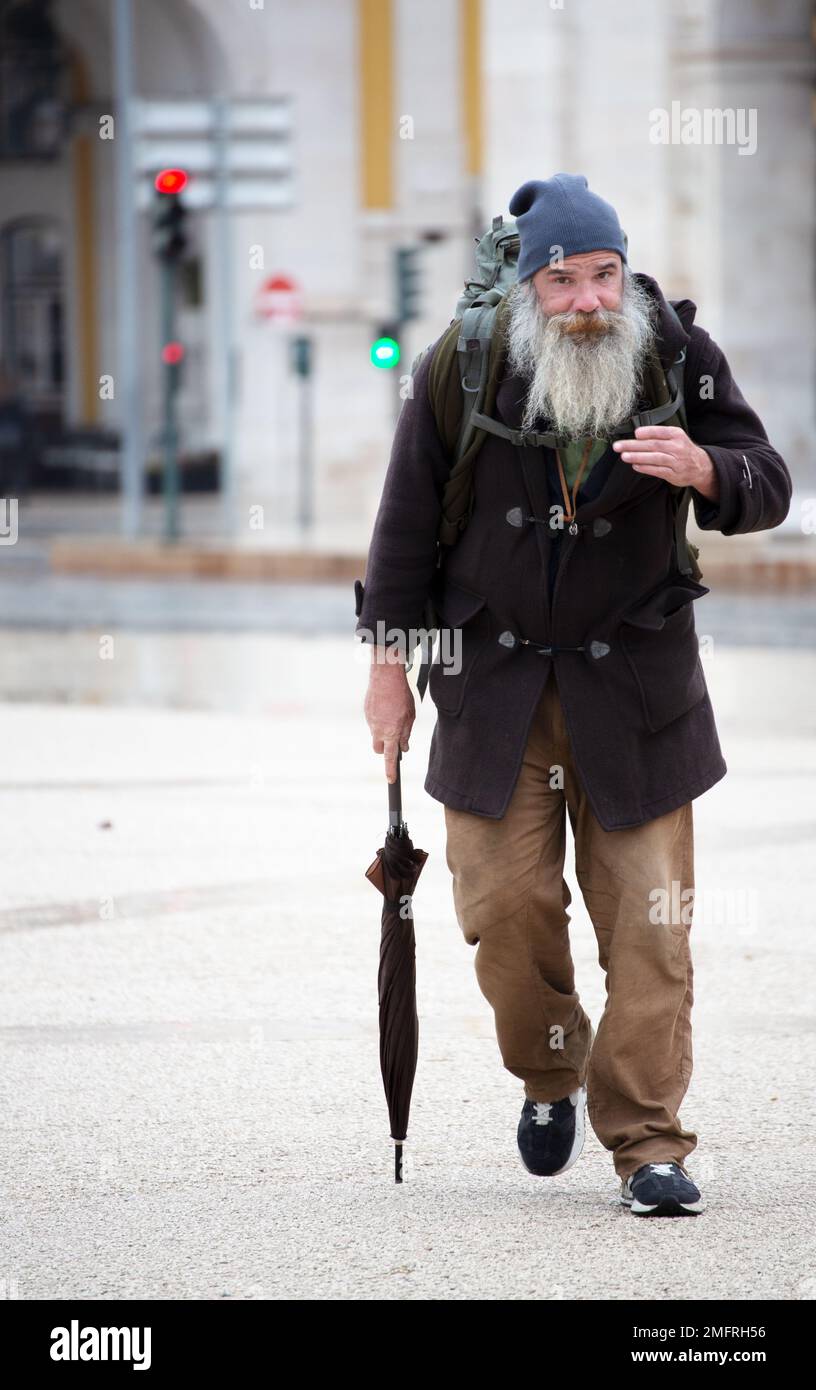 Homme avec une longue barbe en vêtements d'hiver et un grand sac à dos qui marche dans les rues de Lisbonne Banque D'Images