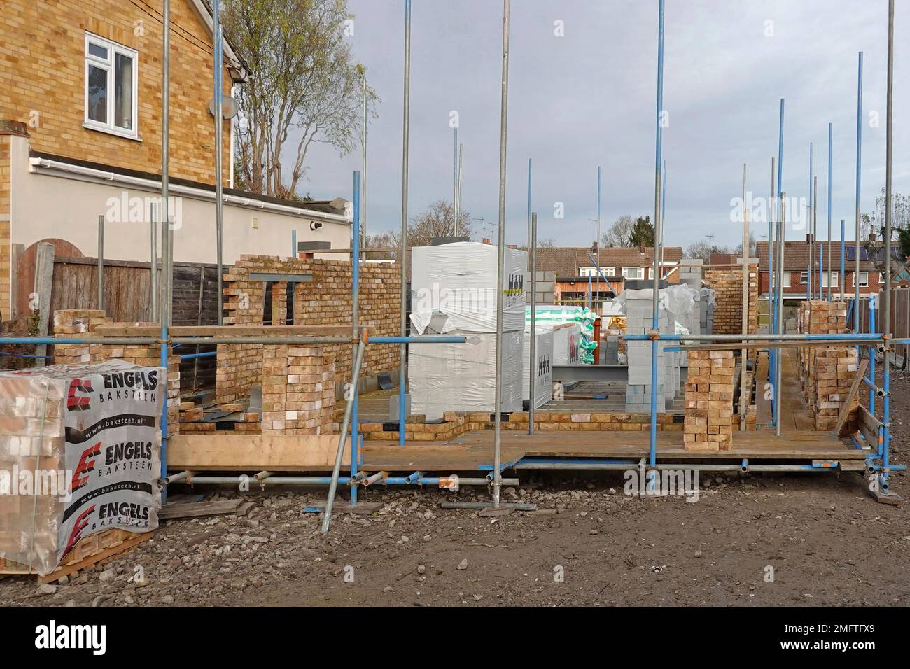 Matériaux de construction empilés sur le chantier de construction de maison travaux en cours sur les murs extérieurs de la cavité de maison individuelle de briques de face et de blocs isolants Royaume-Uni Banque D'Images
