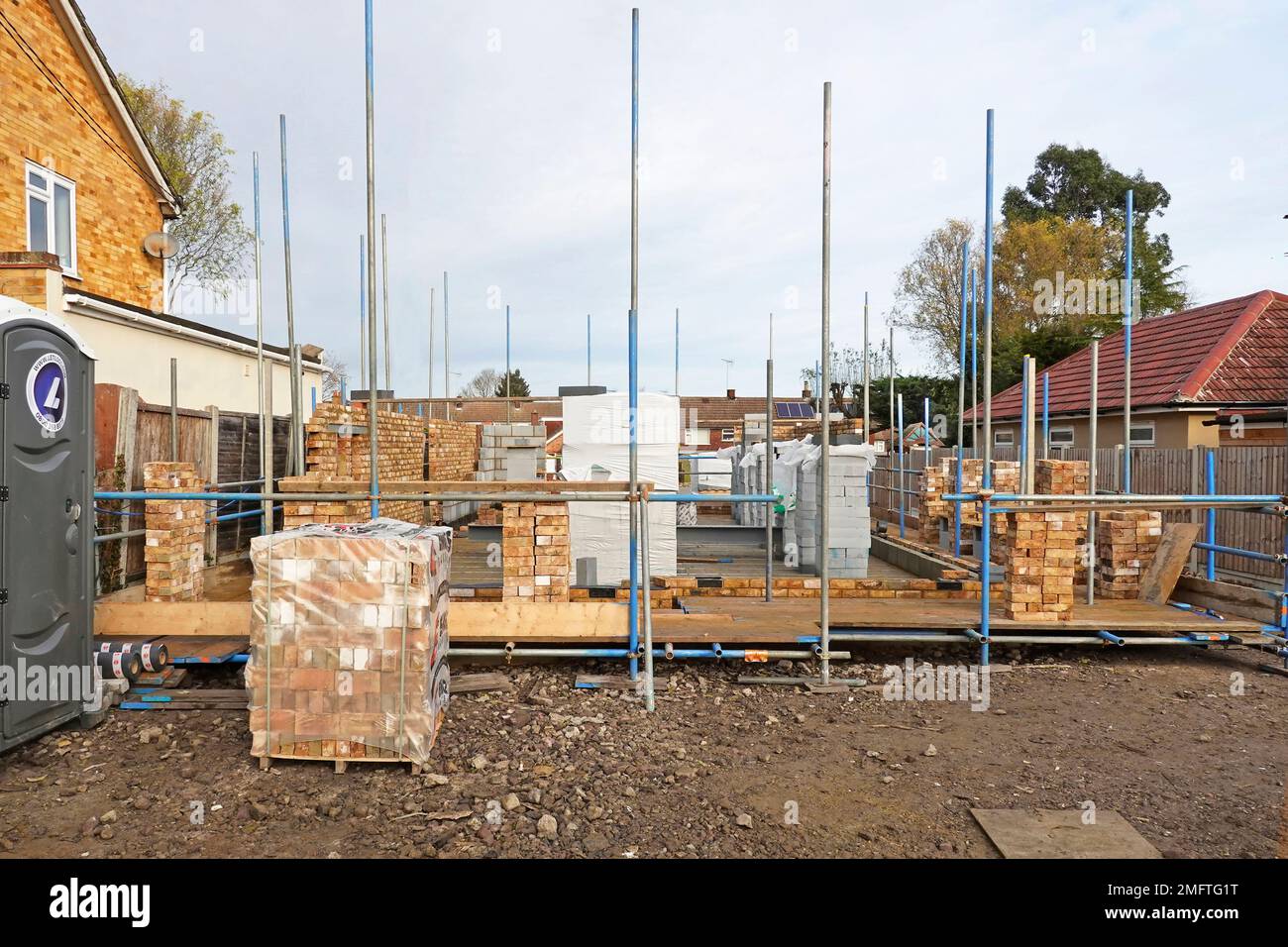Matériaux de construction empilés sur le chantier de construction de maison travaux en cours sur les murs extérieurs de la cavité de maison individuelle de briques de face et de blocs isolants Royaume-Uni Banque D'Images