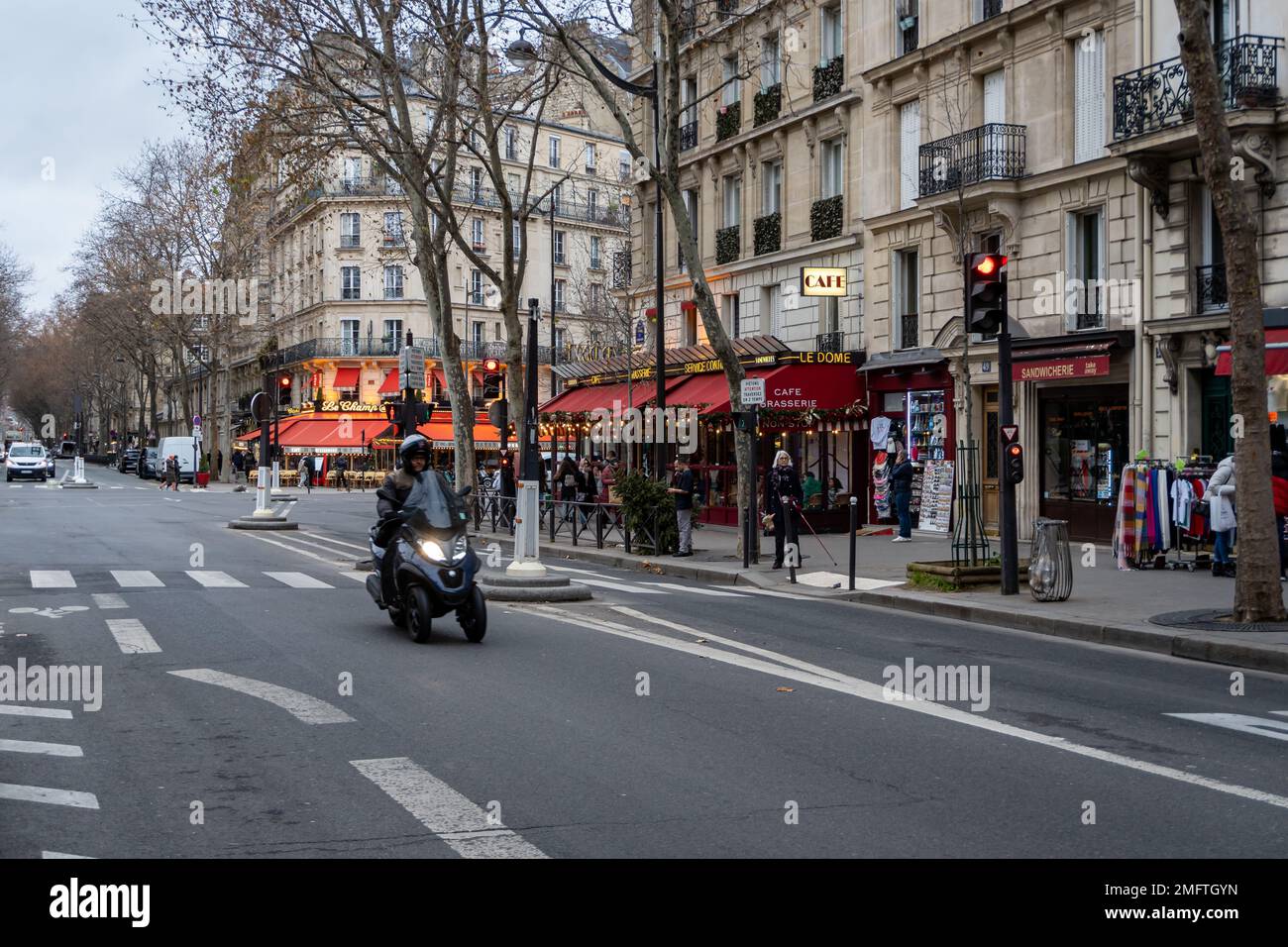 Un scooter à trois roues descend l'avenue de la Bourdonnais en passant devant quelques cafés à Paris, en France. Banque D'Images