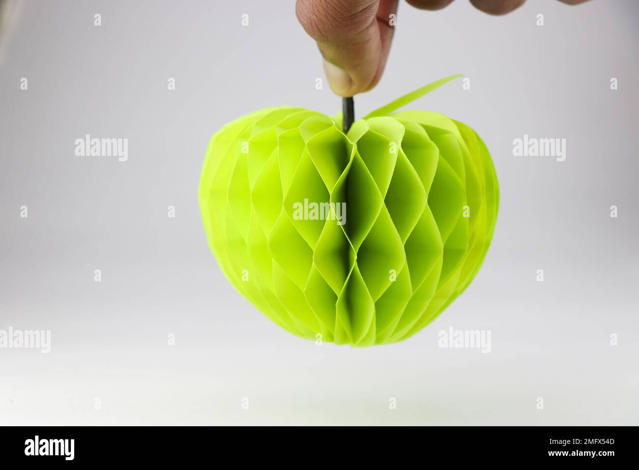 Pomme d'origami ou pomme en papier faite à l'aide de papier couleur tenu à la main avec une vue de sa forme après que le papier a été coupé et collé Banque D'Images