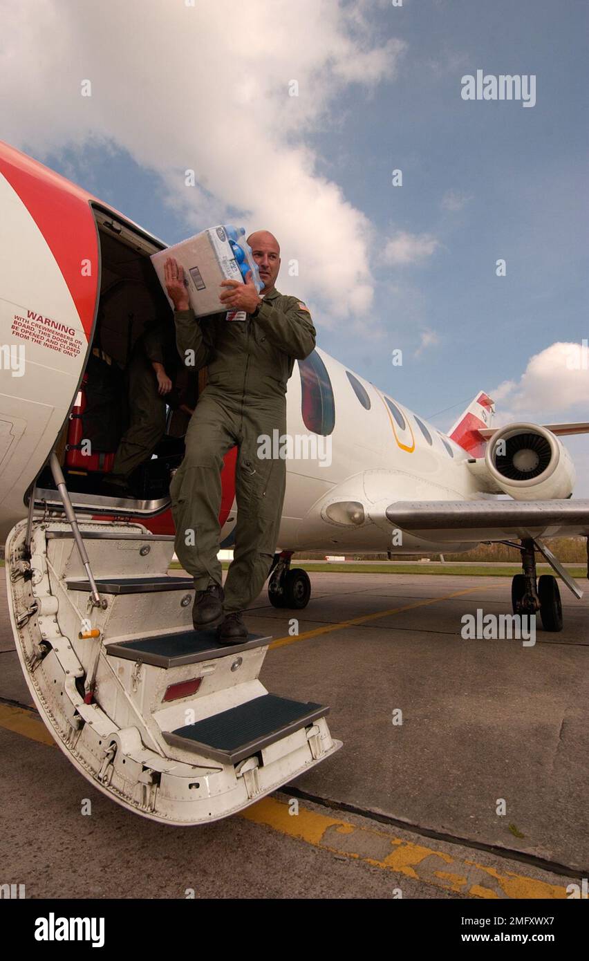 Personnel de la Garde côtière - divers - 26-HK-90-167. Coast Guardsman porte la valise de l'eau sur les marches de l'avion sur la rampe. Ouragan Katrina Banque D'Images