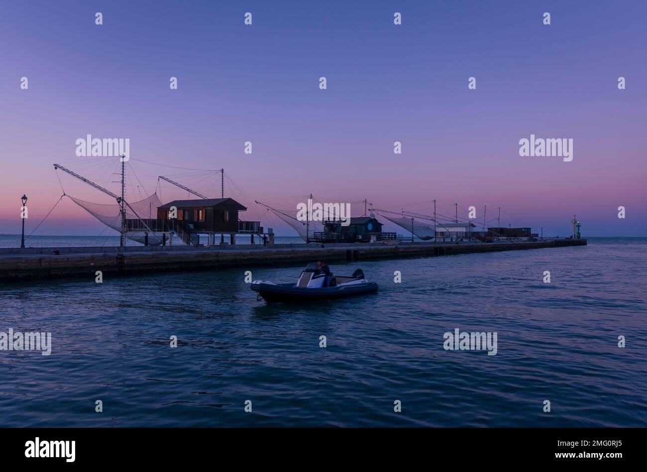 Canal Cesenatico au crépuscule avec cabines de pêche et bateau Banque D'Images