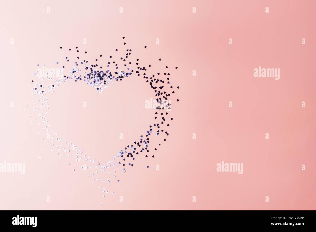 Coeur en confettis d'argent sur fond rose. Concept de vacances de Saint-Valentin. Copier l'espace. Banque D'Images