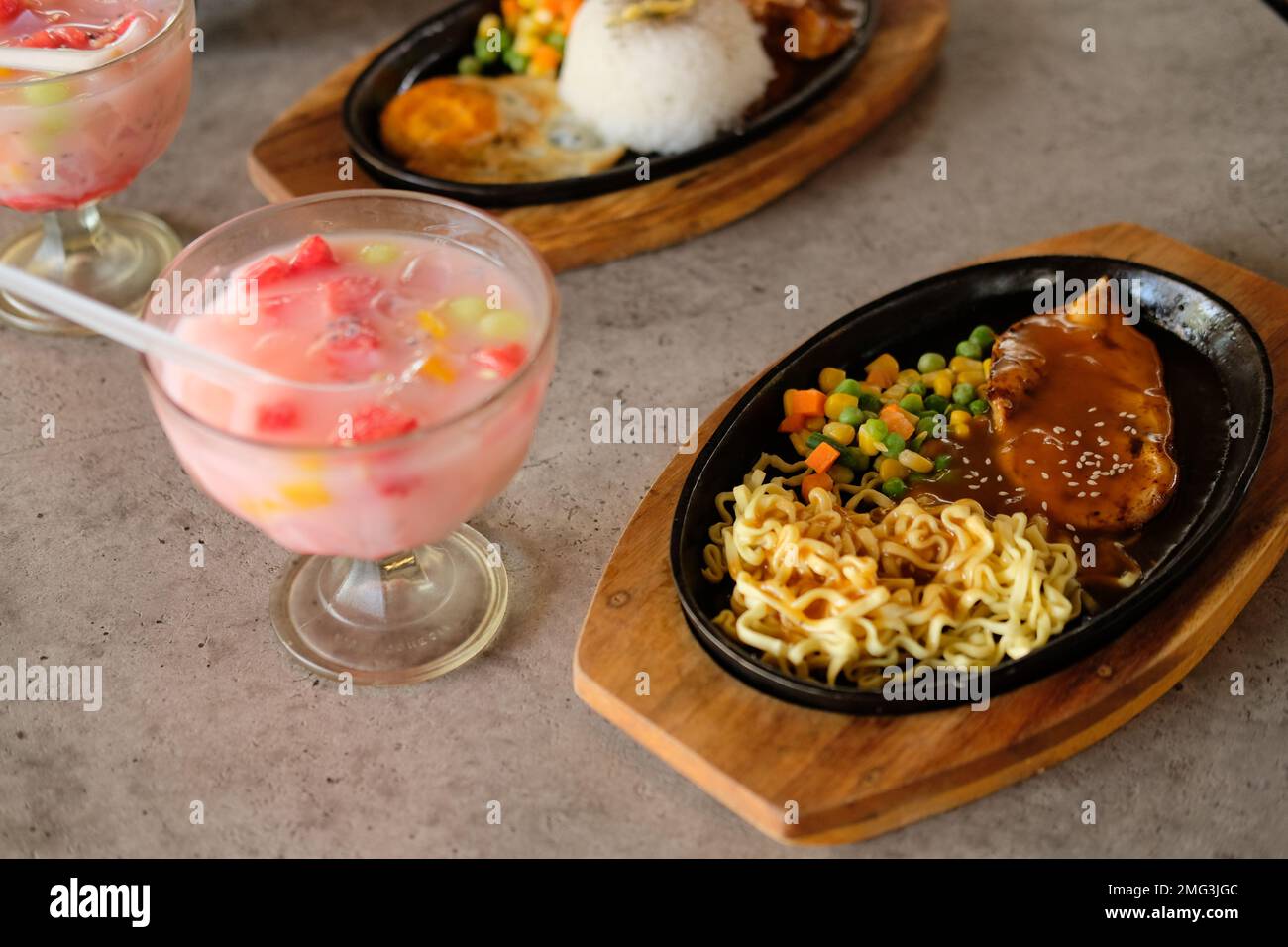 Gros plan d'un bol de nouilles soba avec des tranches de rôti de bœuf et des fruits à glace. Délicieuse cuisine asiatique avec fruits de glace sur la table Banque D'Images