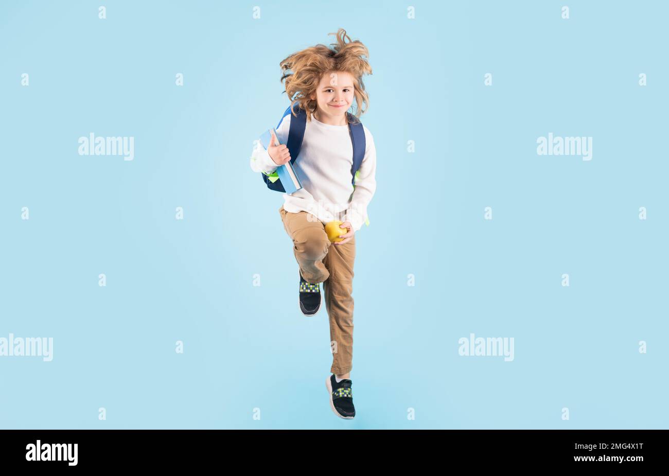 Les enfants sautent et aiment l'école. Corps entier de petit enfant d'école saut ayant amusant isolé fond bleu. Saut fou de garçon d'école. Banque D'Images