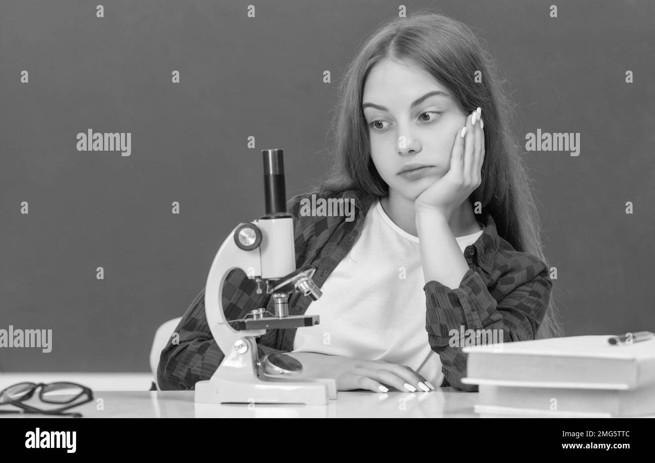 enfant fatigué avec microscope en classe au tableau noir, biologie Banque D'Images