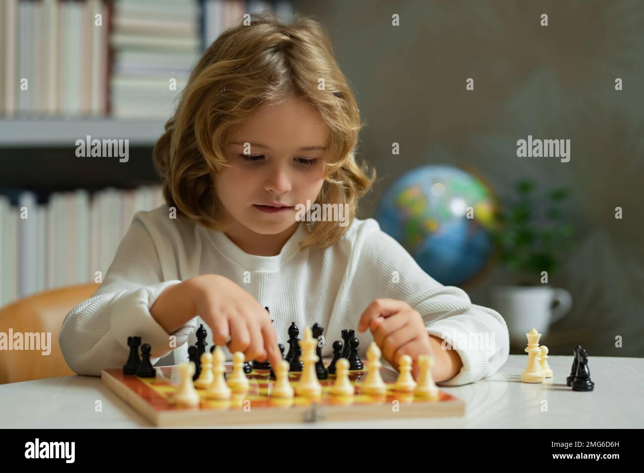 École d'échecs. Échecs de jeu d'enfant concentré. Enfant jouant à un jeu de société en classe. Banque D'Images