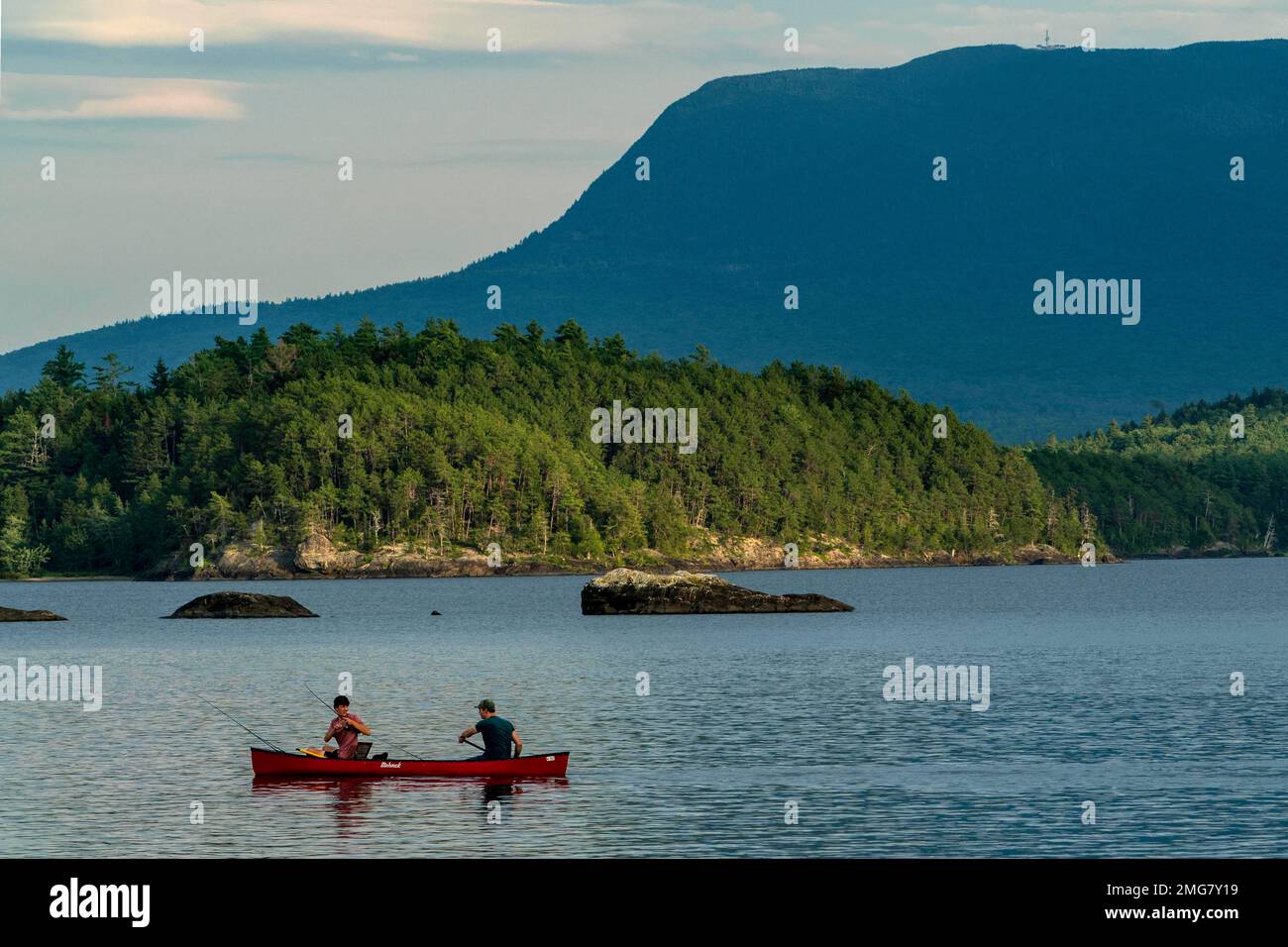 A man fishes from the bow of a canoe on Lobster Lake, Thursday, Aug. 13, 2020, in Lobster Township, Maine. Water levels in the lake are low this summer. The high water mark can be seen on the rock at center. (AP Photo/Robert F. Bukaty) Banque D'Images