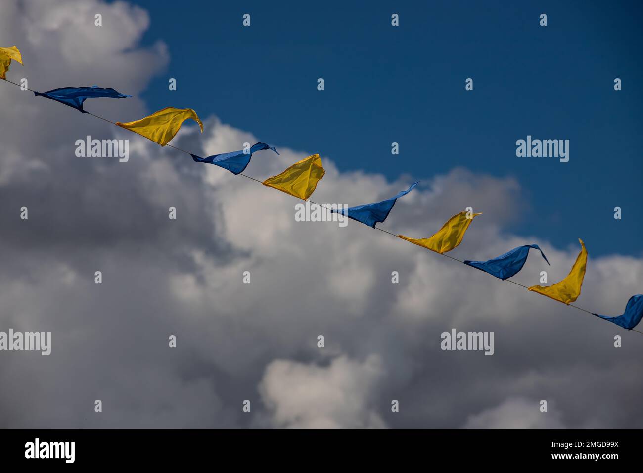 Drapeaux triangulaires jaune et bleu sur fond de ciel avec nuages blancs. Fête en plein air. Ambiance festive Banque D'Images