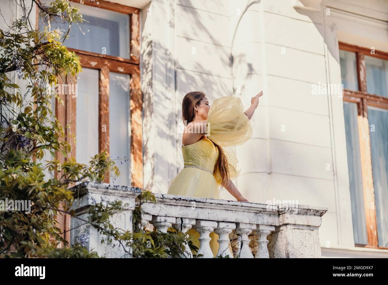 une belle femme souriante et gentille dans une magnifique robe jaune se dresse sur le balcon d une ancienne maison d epoque Photo Stock Alamy