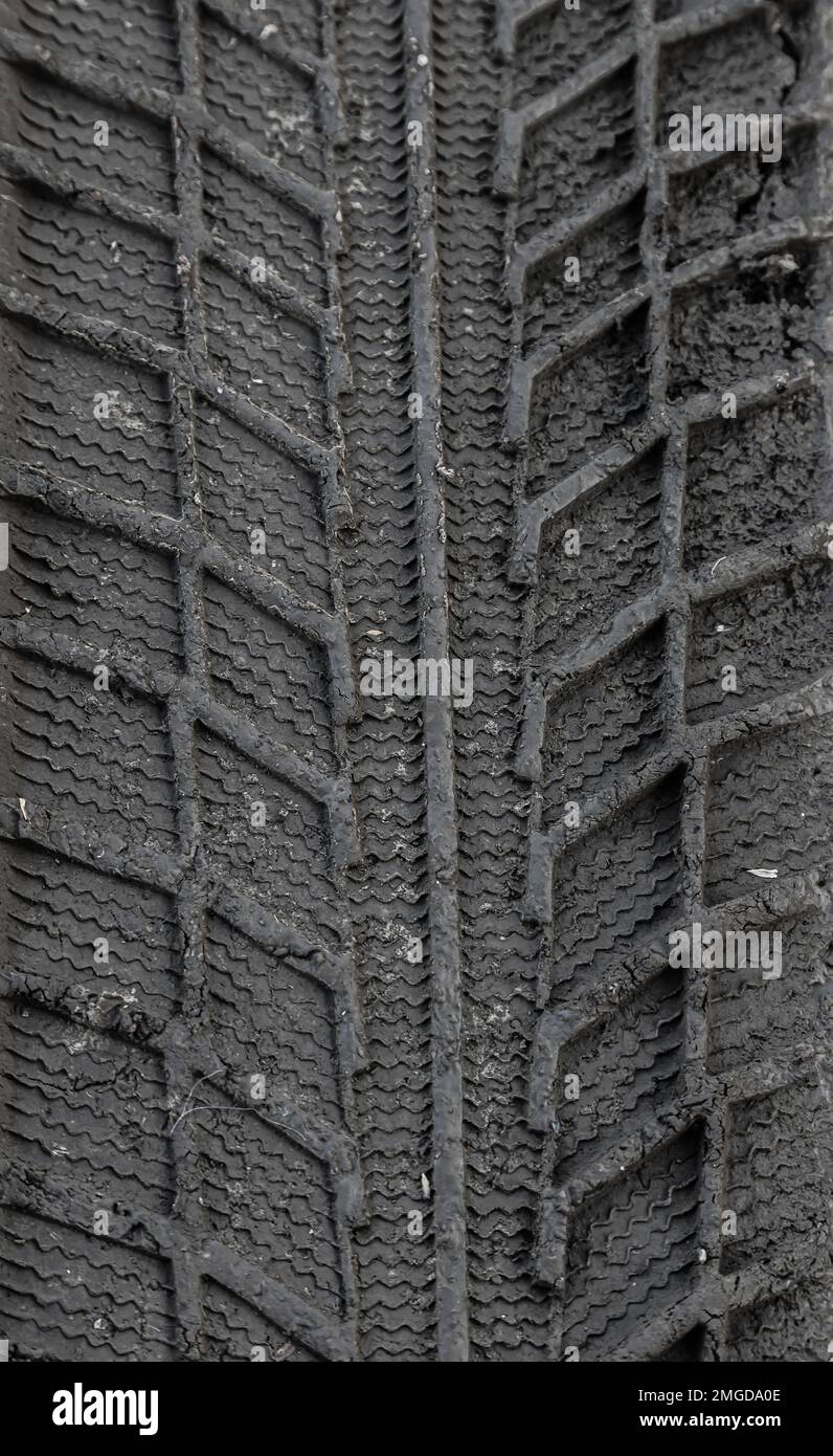 Traces de bande de roulement de pneu de voiture dans le sol. Répétition. Arrière-plan abstrait sombre. Impression des roues. Sol texturé. Dessin des pneus. Banque D'Images