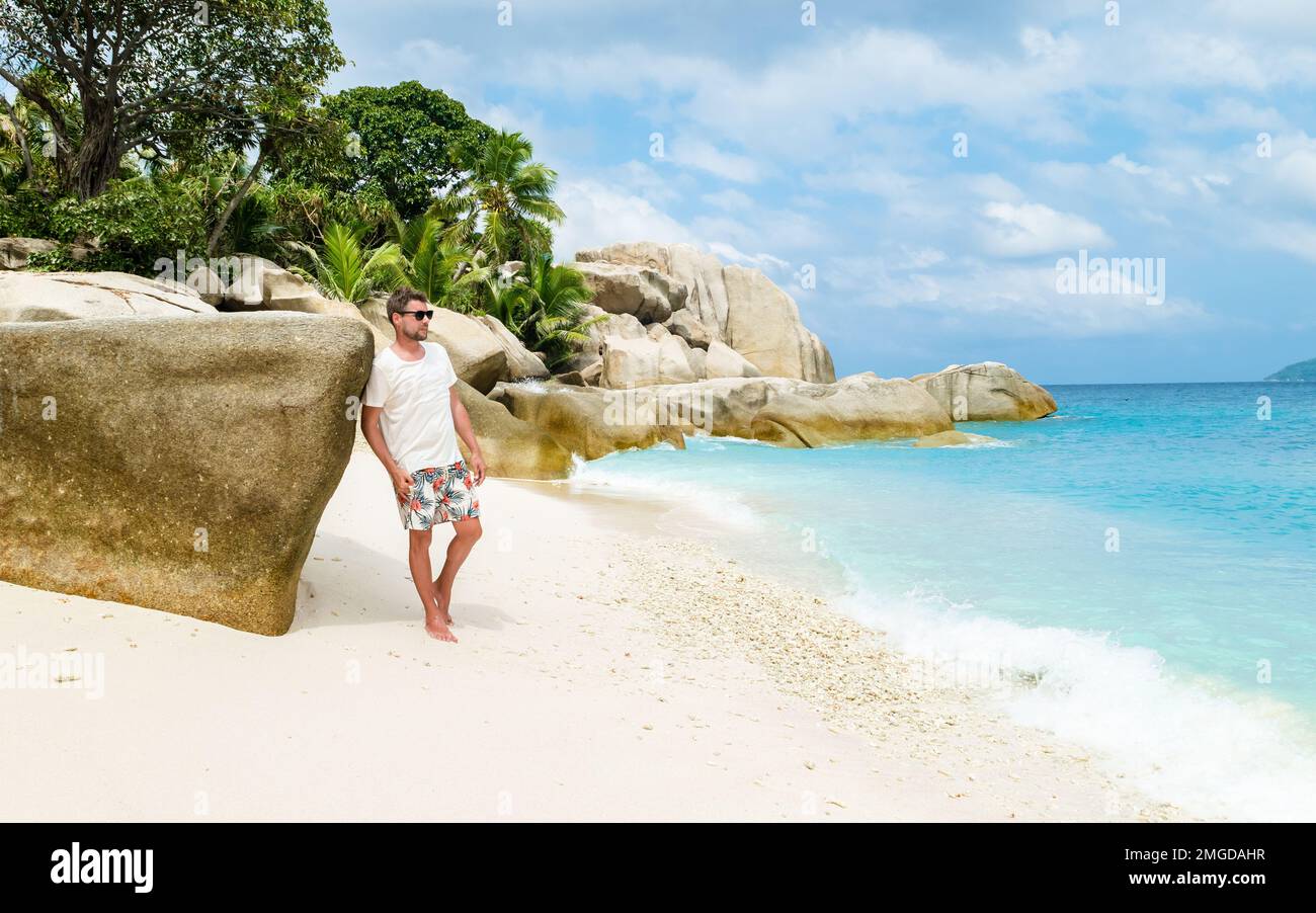 Jeunes hommes sur une plage tropicale blanche avec des palmiers Coco Island Tropical Seychelles Islands. Banque D'Images