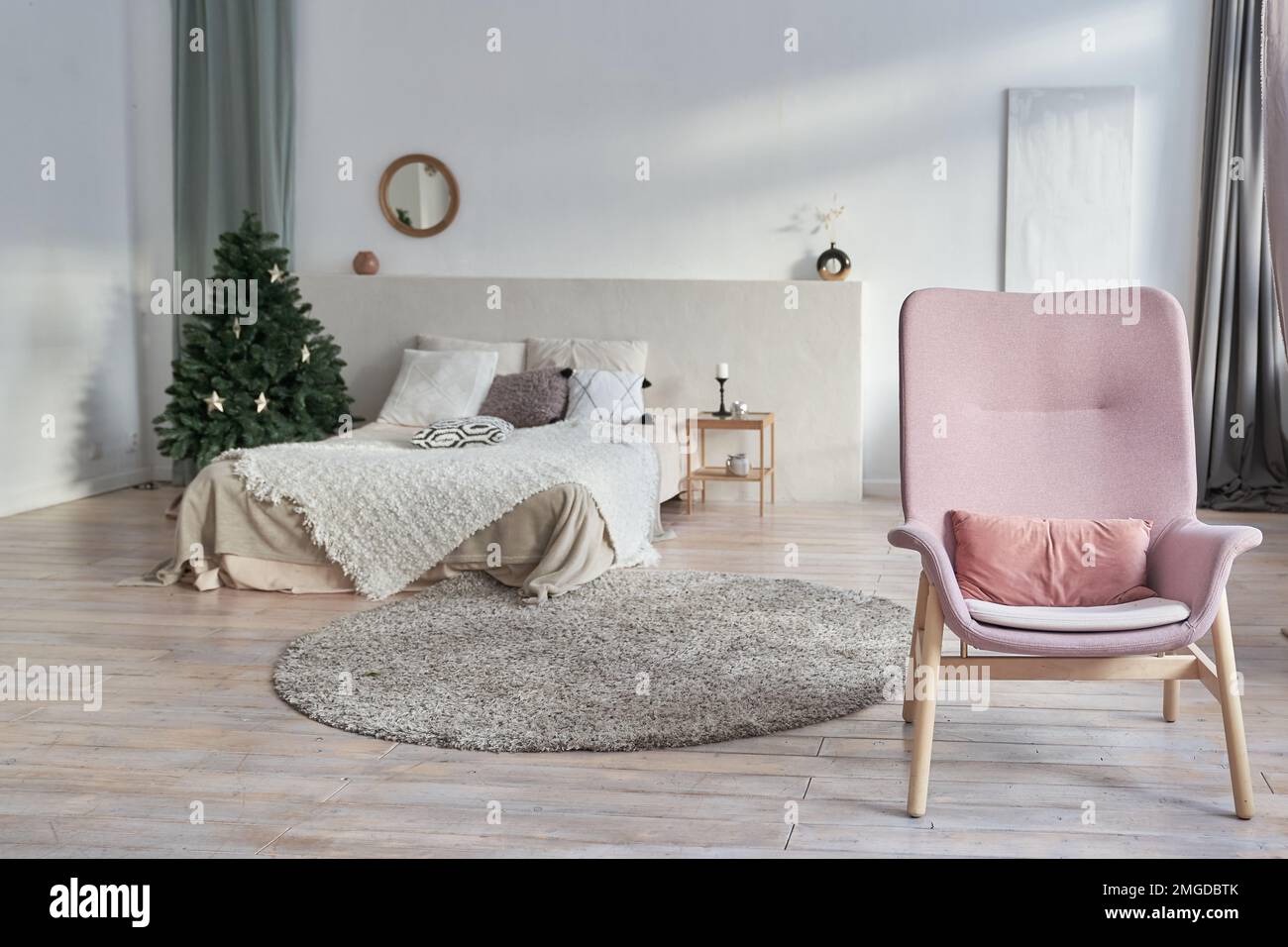 Intérieur confortable avec une chaise au premier plan. Sapin de Noël dans une chambre confortable le réveillon de Noël. Arrière-plan avec un lit avec espace à copier. Photo de haute qualité Banque D'Images Intérieur confortable avec une chaise au premier plan. Sapin de Noël dans une chambre confortable le réveillon de Noël. Arrière-plan avec un lit avec espace à copier. Photo de haute qualité Banque D'Images