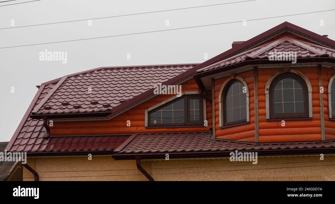 Le toit de la maison est fait de carreaux de métal rouge, une belle grande cheminée. Banque D'Images