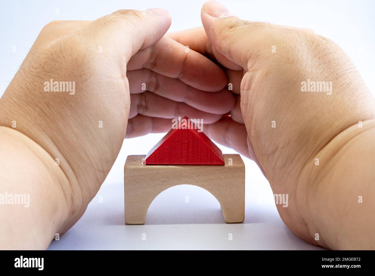 Maison modèle en bois couverte par la main de l'homme pour la protection. Assurance de biens, concept d'investissement immobilier. Banque D'Images