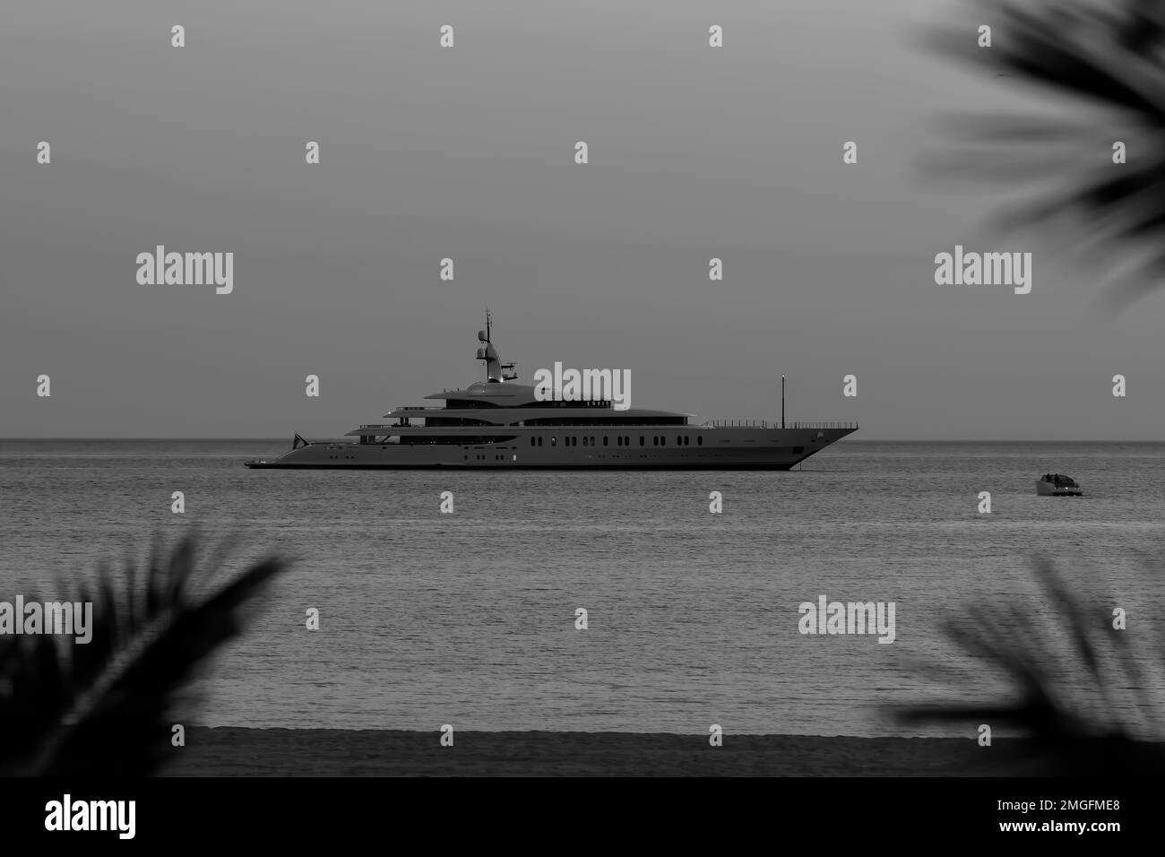 IOS, Grèce - 3 juin 2021 : vue sur un yacht de luxe à la célèbre plage de Mylopotas à iOS Grèce et un coucher de soleil violet en noir et blanc Banque D'Images