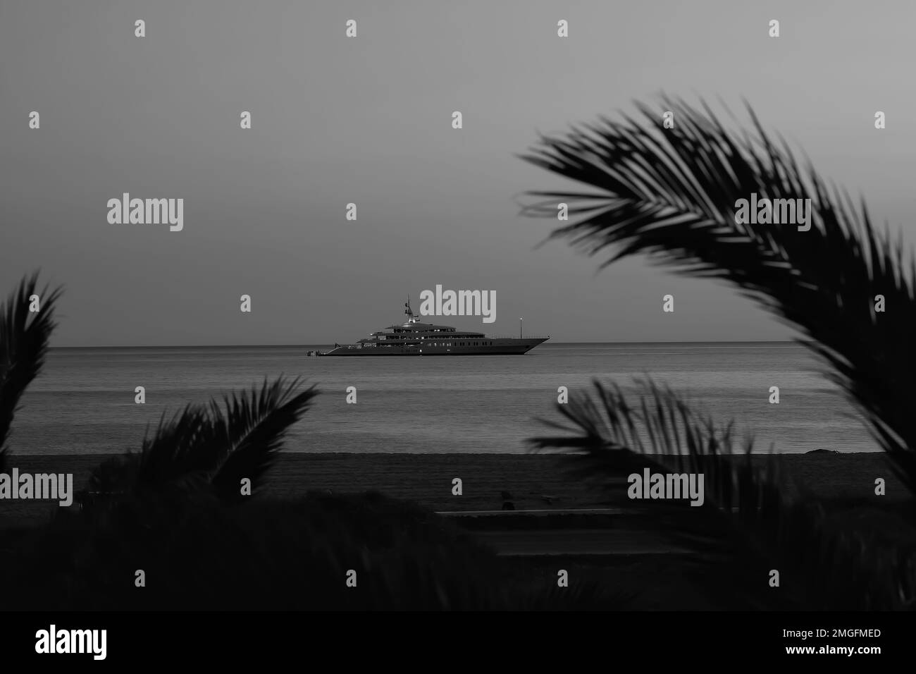 IOS, Grèce - 3 juin 2021 : vue sur un yacht de luxe à la célèbre plage de Mylopotas à iOS Grèce et un coucher de soleil violet en noir et blanc Banque D'Images