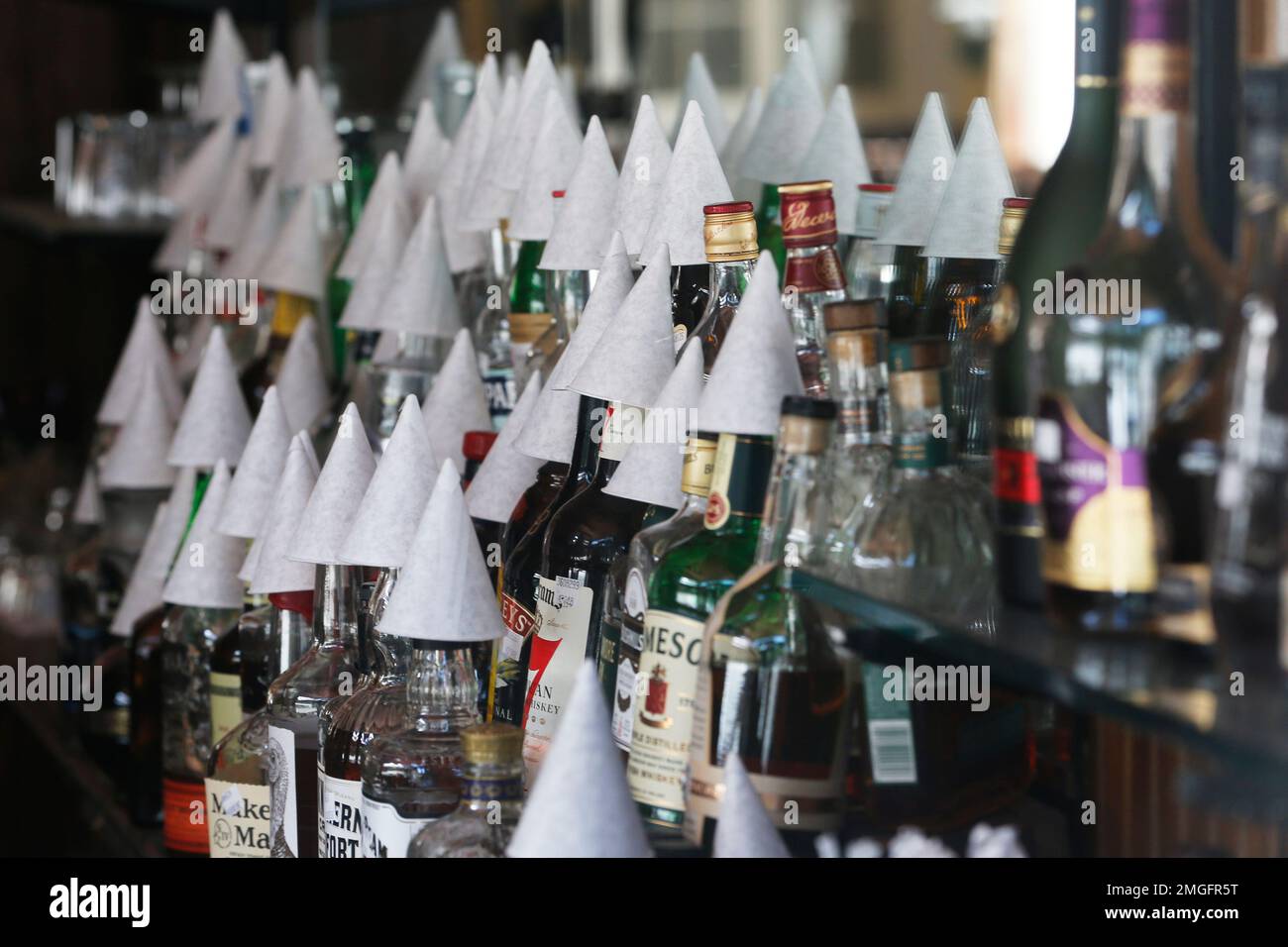 FILE - In this Thursday, May 7, 2020, file photo, cups cover liquor bottles at the closed Tarrant's Café restaurant in Richmond, Va. More than two months after the coronavirus pandemic started forcing Virginia businesses to slash their workforces, the state's unemployment system still can't keep up with the unprecedented deluge of calls and emails from laid-off workers who need help. (AP Photo/Steve Helber, File) Banque D'Images