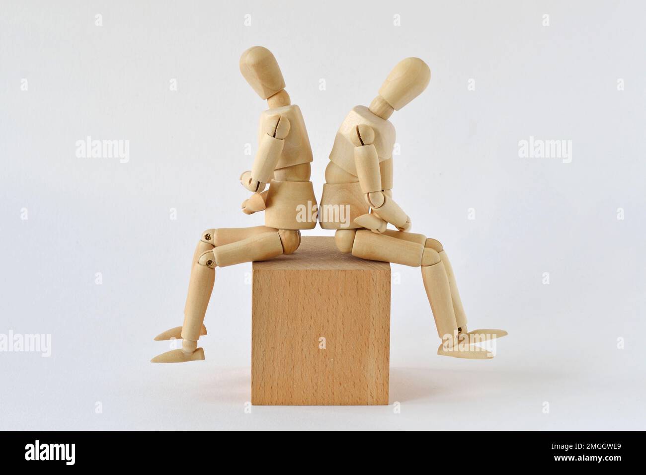 Deux mannequins en bois assis dos à dos sur un bloc de bois - concept de querelle et des problèmes de relation Banque D'Images
