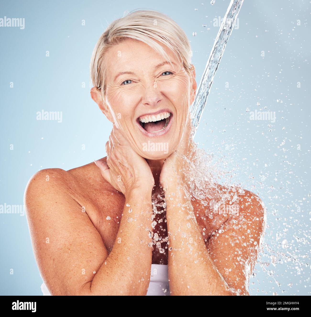 Portrait, vieille femme et éclaboussures d'eau pour le nettoyage, soin de la peau ou femme sourire sur fond gris studio. Femme en bonne santé, âgée ou liquide pour se laver Banque D'Images